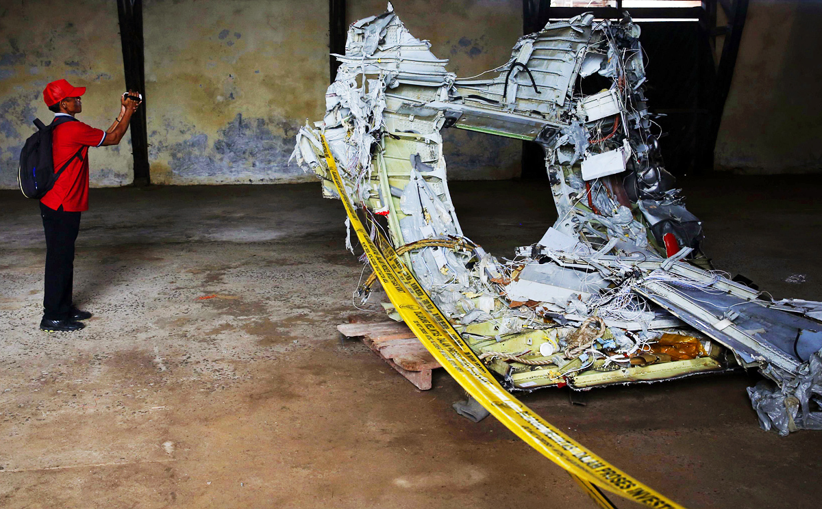 A man shoots video footage of part of the fuselage of crashed AirAsia Flight QZ8501 inside a storage facility at Kumai port in Pangkalan Bun. Photo: Reuters