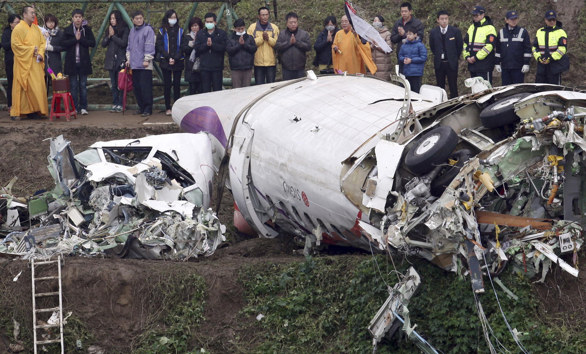 Relatives of victims of the TransAsia Airways crash pray on the banks of the Keelung River near the plane's wreckage yesterday. Photo: AP