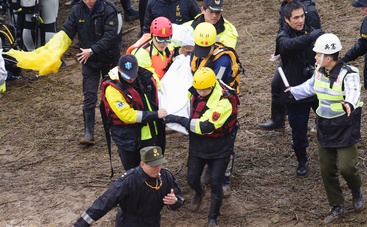Workers carry a body away from the crash site. Photo: AFP