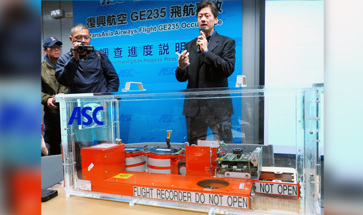 Thomas Wang (right), executive director of the Aviation Safety Council, standing behind a black box, reveals initial findings from the crash. Photo: EPA