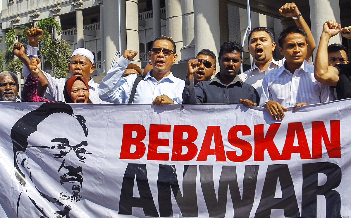 Supporters of Malaysian opposition leader Anwar Ibrahim hold a banner  reading 'Free Anwar' during a court case against Foreign Affairs Minister Anifah Aman in the Duta Court Complex, Kuala Lumpur on Febuary 17, 2015. Photo: EPA