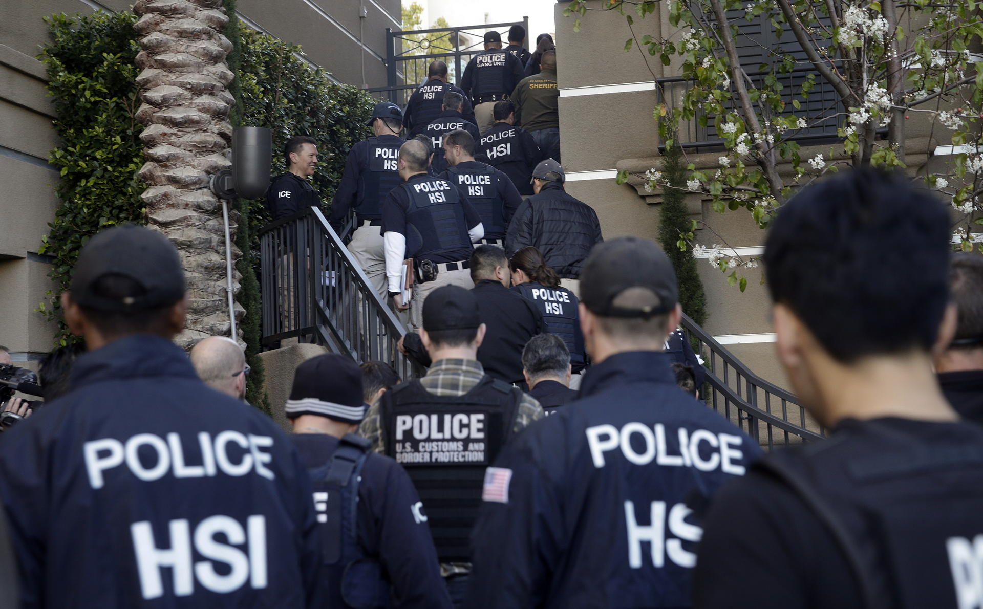 Federal agents (left) swarm on upscale an apartment complex believed to be a birth tourism business in Irvine, California. Photo: AP