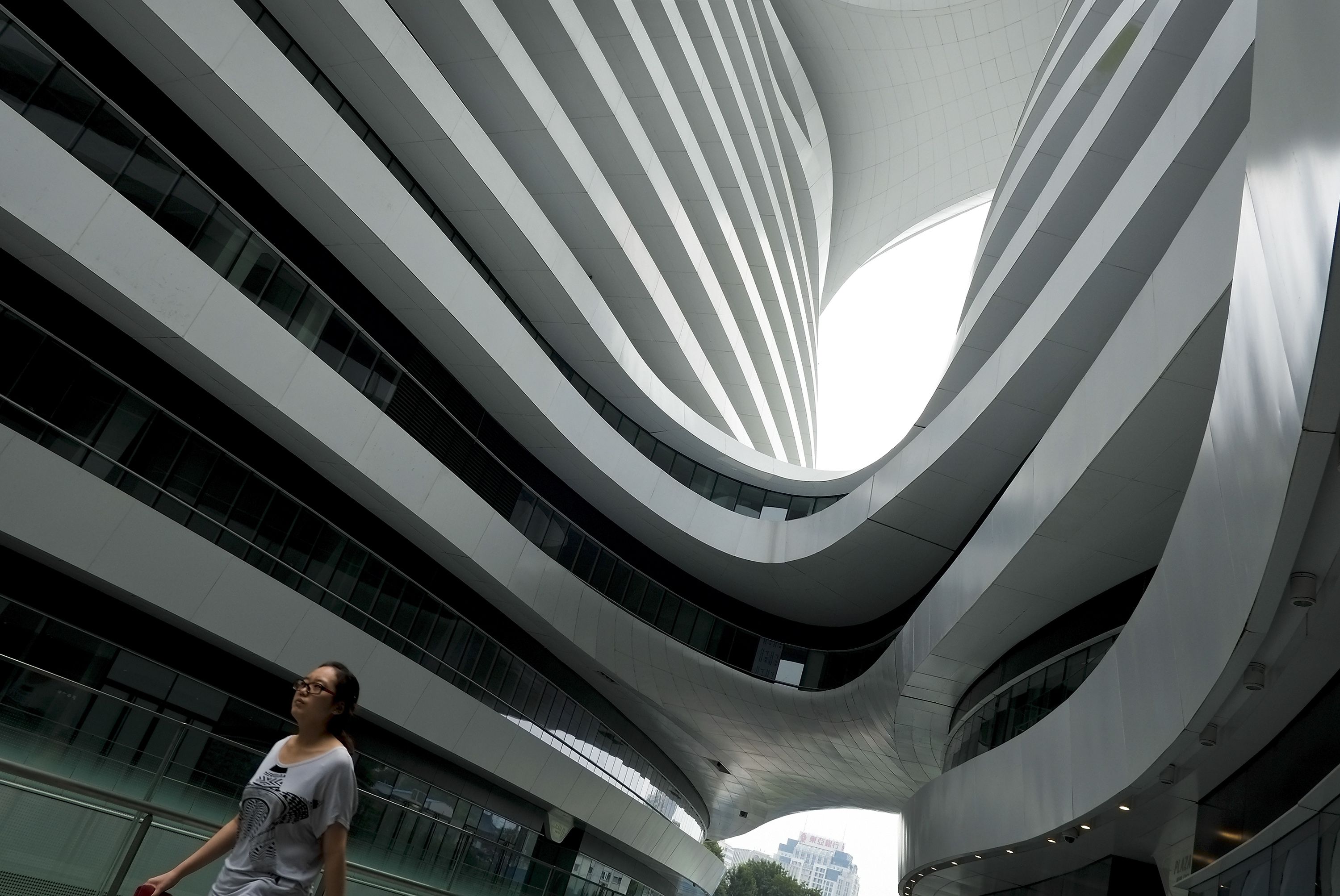 A woman walks past an office building in Beijing. Mainland China's biggest developer of prime office space, Soho China, reported a near 60 per cent fall in core profit. Photo: AP
