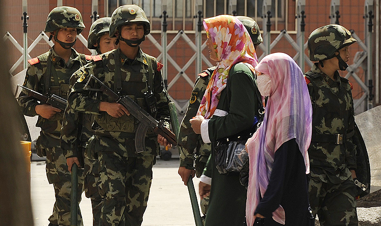 Uygur women pass a paramilitary police patrol on a street in Urumqi, the capital of Xinjiang. Photo: AFP