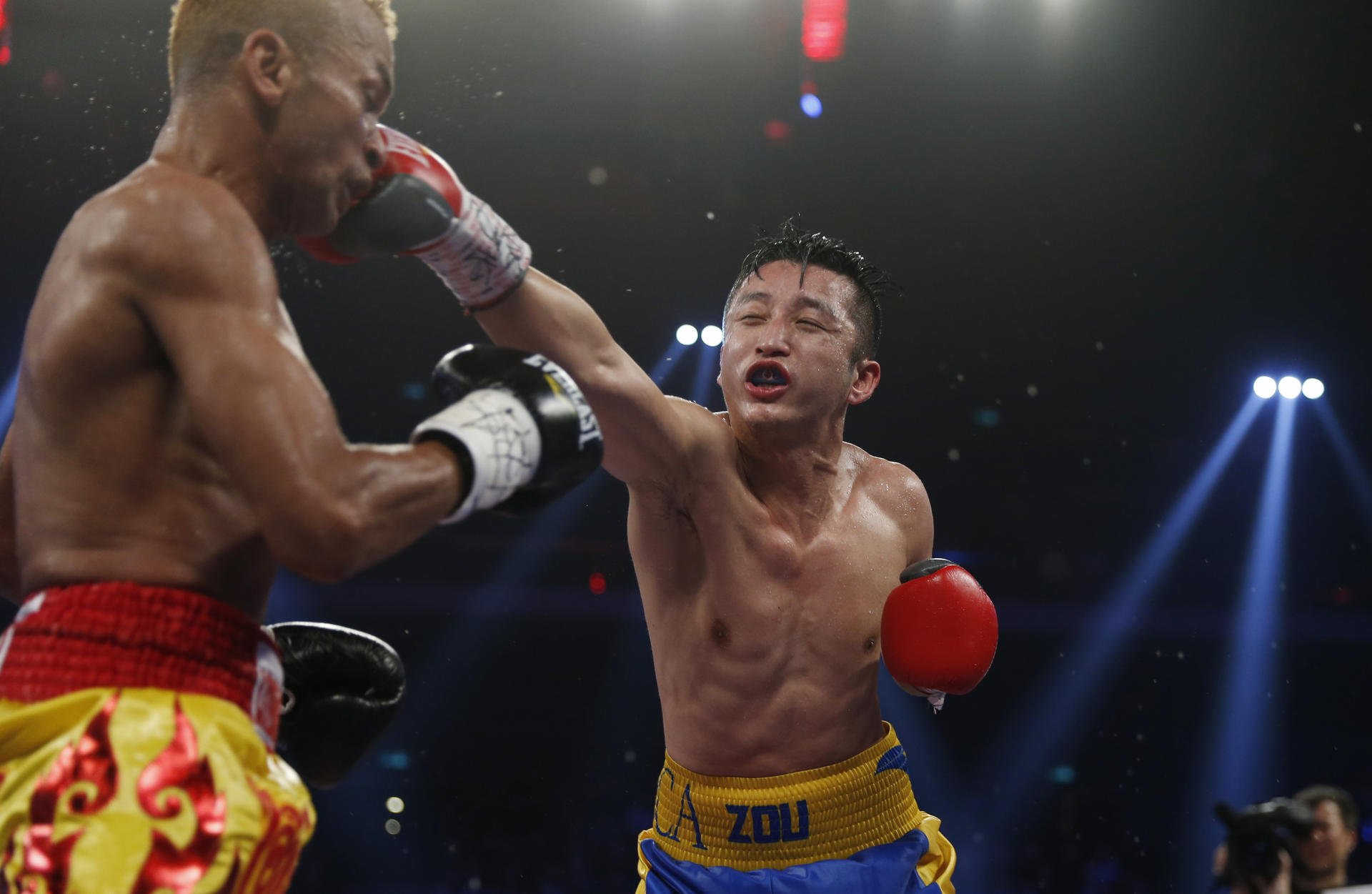 China's Zou Shiming hits out at Thailand's Amnat Ruenroeng during their IBF flyweight world title bout in Macau last night. Photo: AP