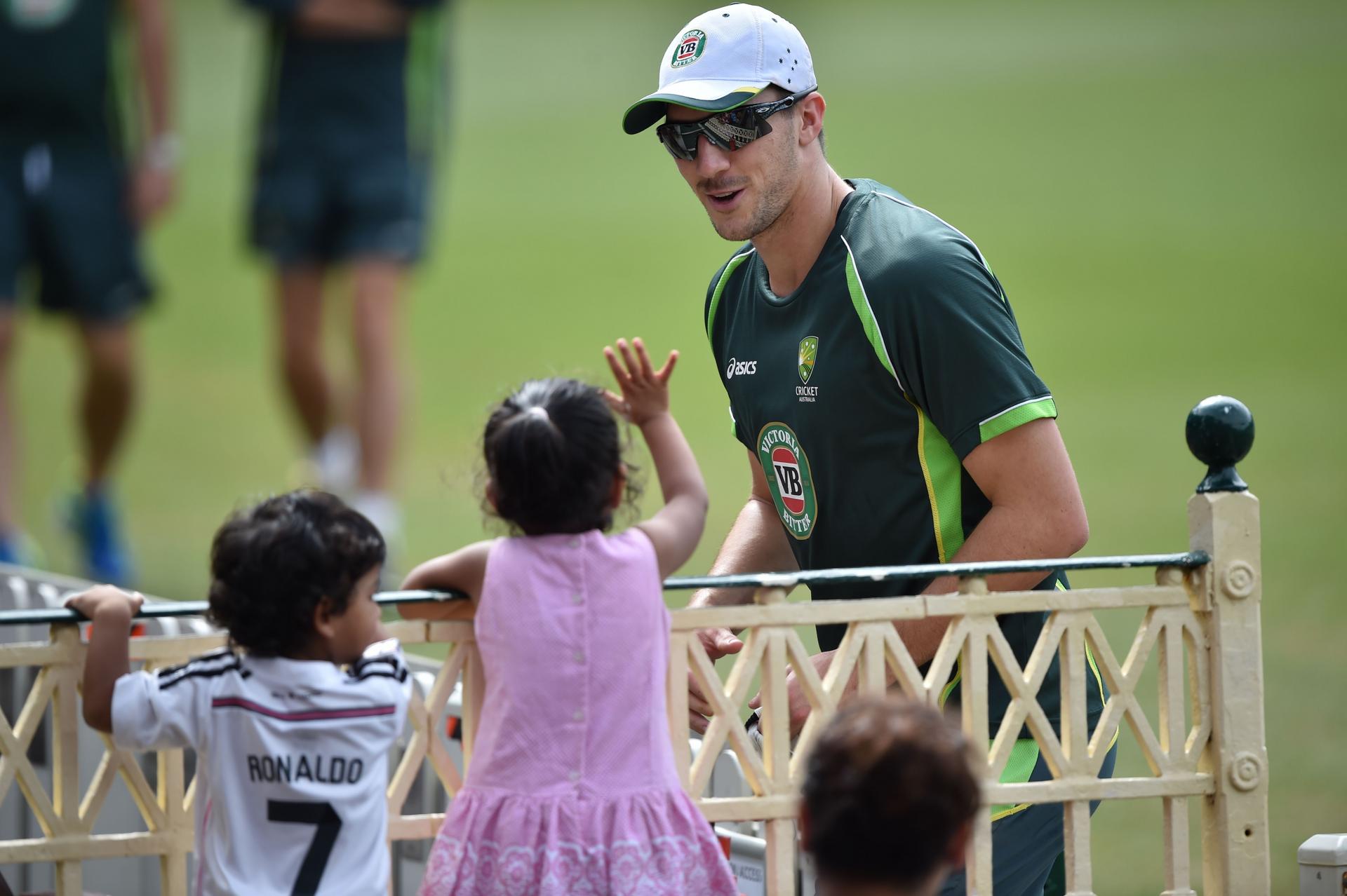 Australia bowler Pat Cummins interacts with a young fan during a training session. Photo: AFP