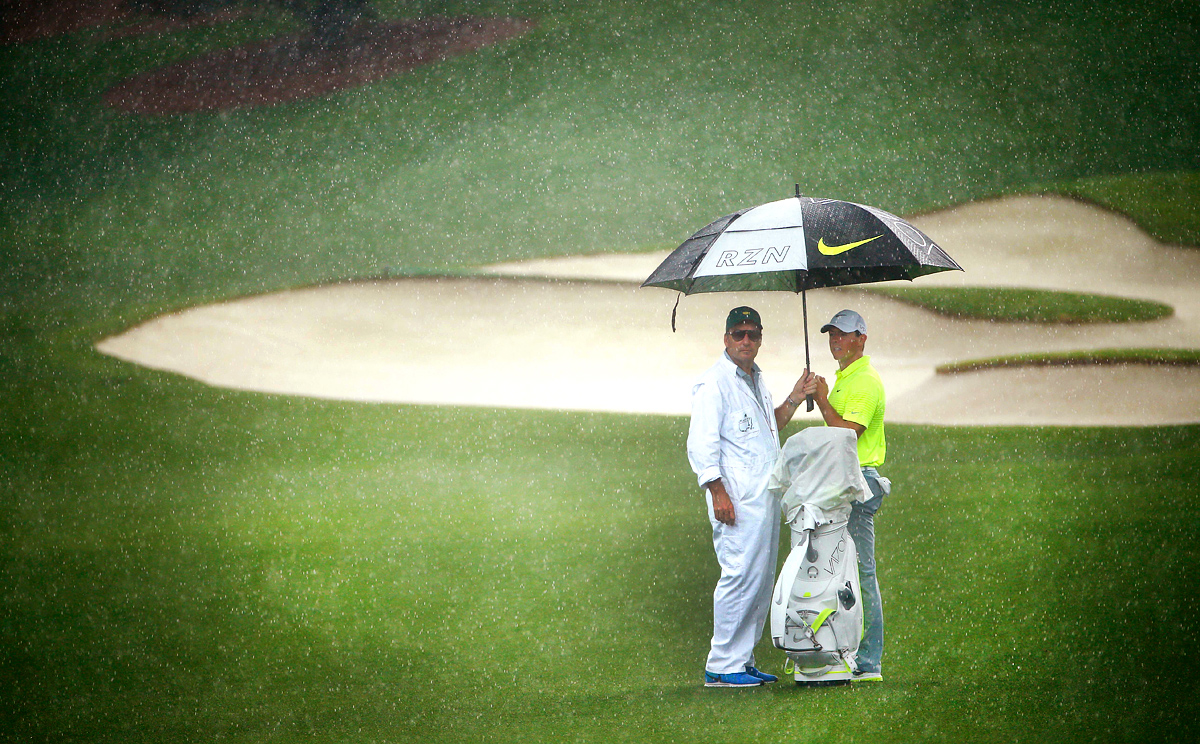 Rory McIlroy and his caddie practise in the rain. Photo: AFP