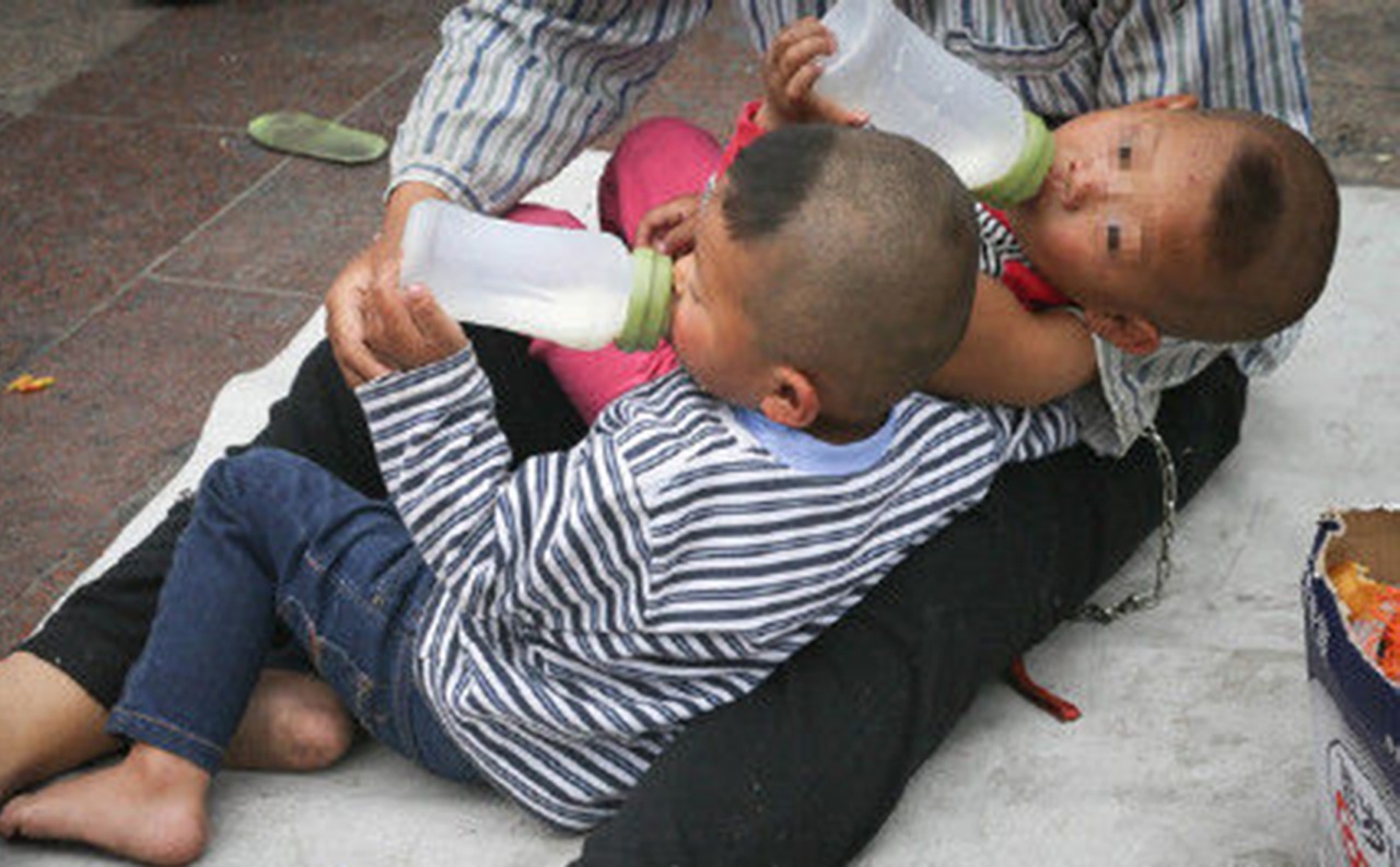 The beggar chained his two children to him outside a Beijing train station. Photo: SCMP Pictures