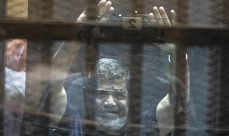 Mohammed Mursi raises his hands as the judge reads out the verdict sentencing the ousted president and more than 100 other defendants to death. Photo: AFP