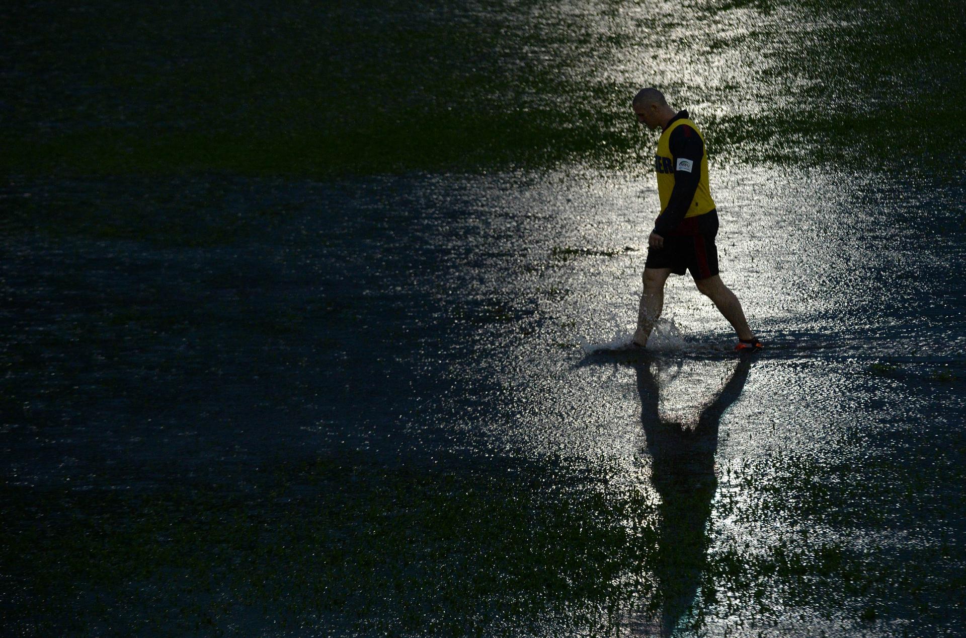 A trainer inspects the field during the Asia Rugby Championship clash between Hong Kong and Japan at Aberdeen. Officials eventually decided to abandon the match, which was halted after 13 minutes. Photo: AFP