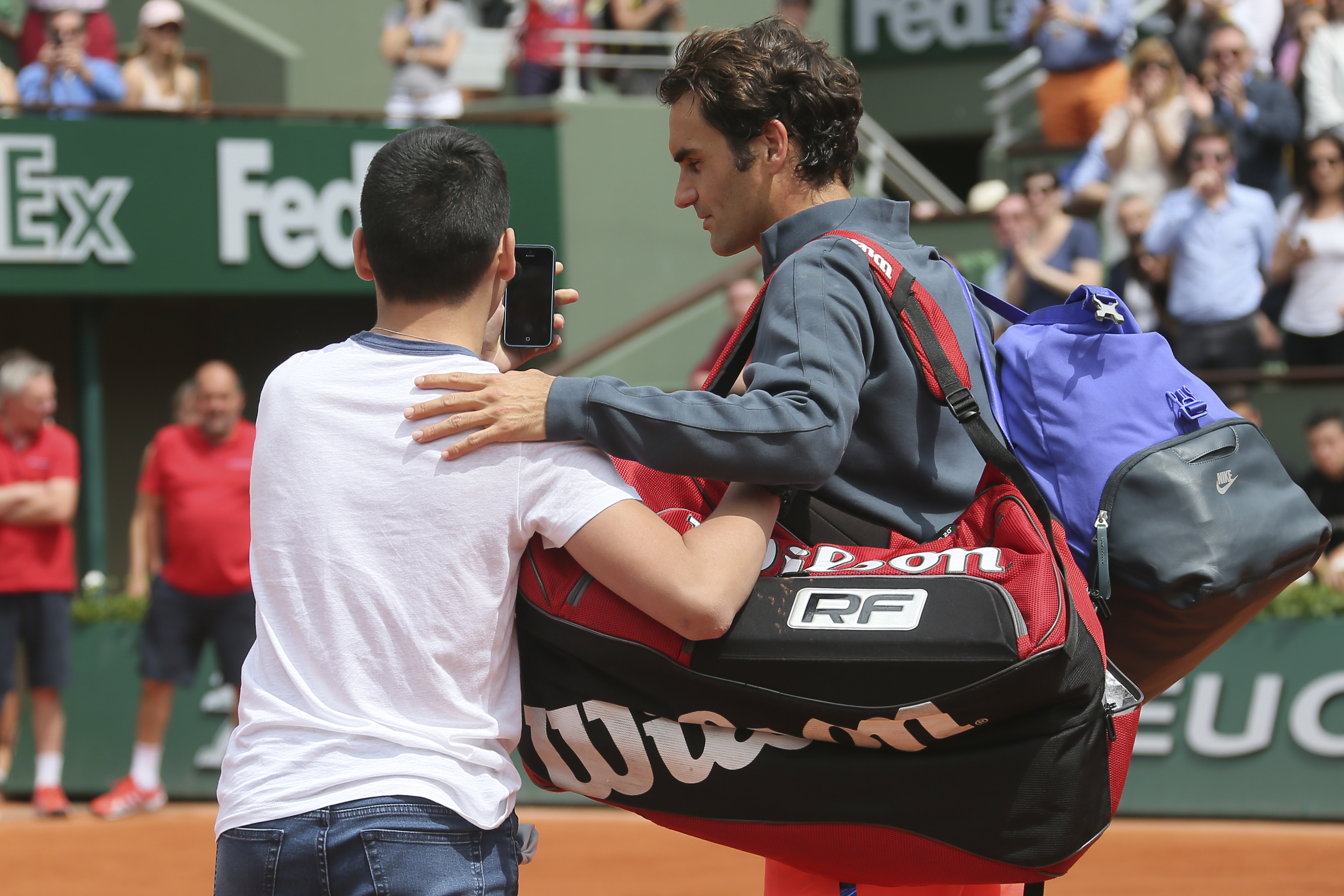 A boy tries to take a selfie with Roger Federer on centre court at the French Open. Federer had just won his first-round match against Colombia's Alejandro Falla when the teenager confronted him. Photo: AP