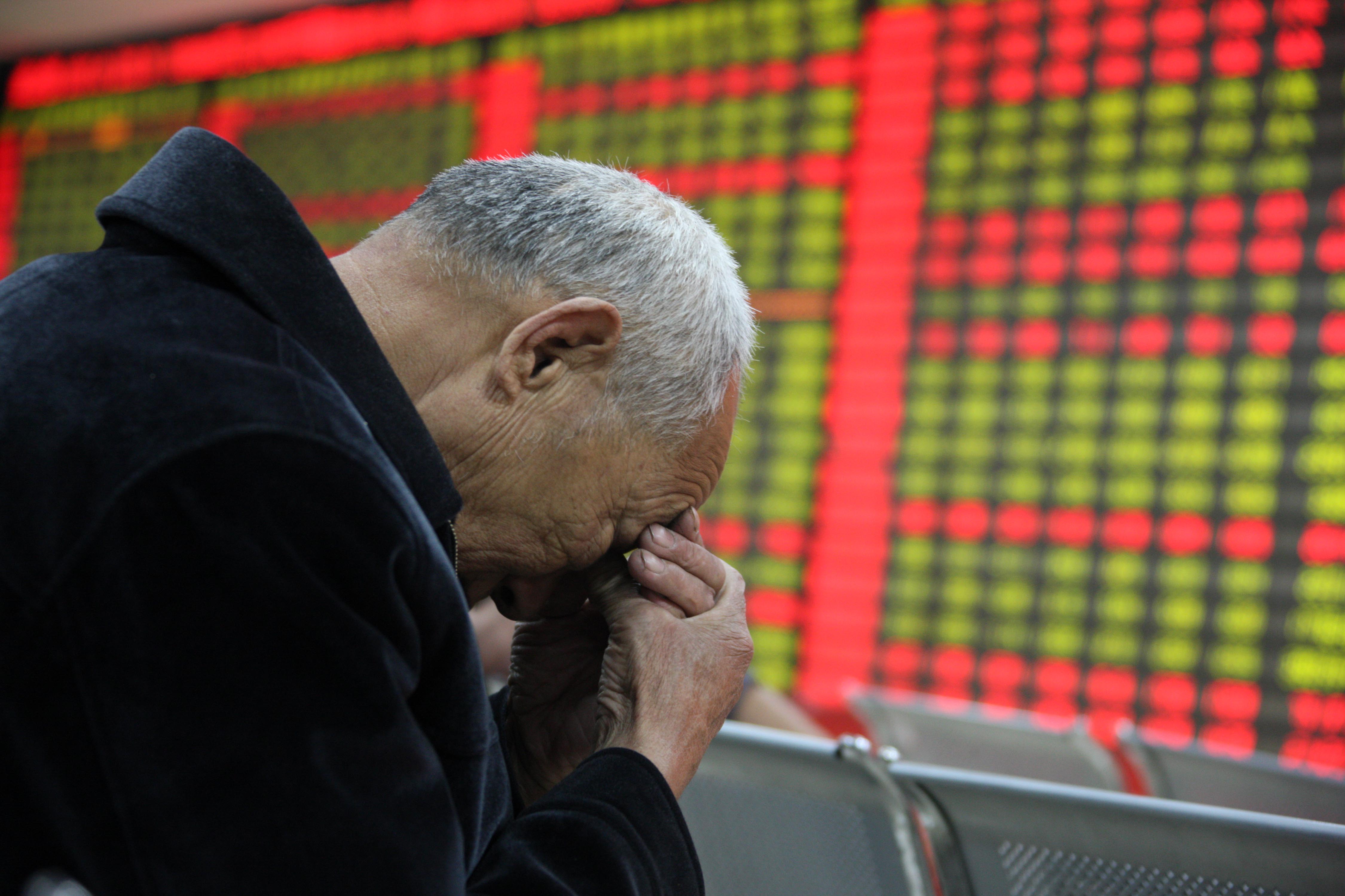 An elderly Chinese investor rubs his forehead underneath an electronic board showing stock prices. Analysts fret that small cap stocks in Hong Kong and on the mainland are in bubble territory. Photo: Xinhua