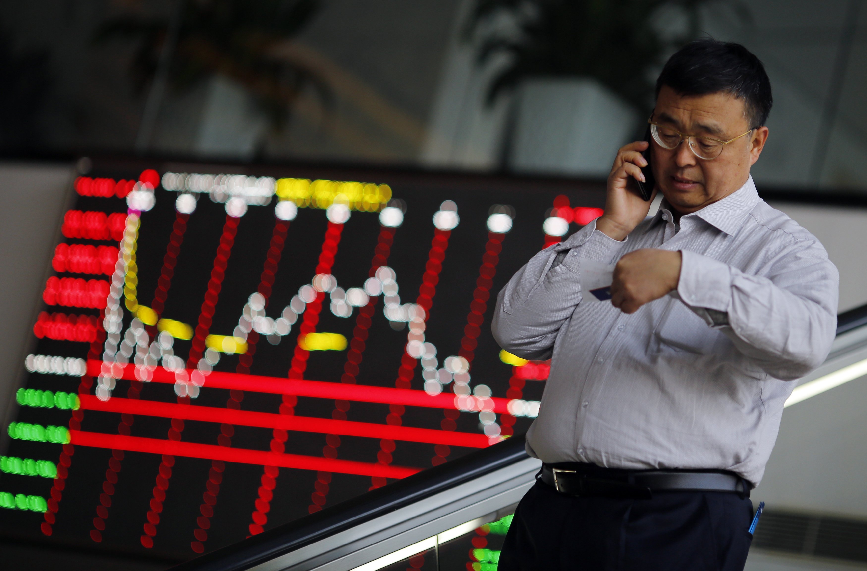 A man talks on his cell phone inside the Shanghai Stock Exchange building in the city's Pudong financial district. Chinese markets open mixed as punters digested the latest liberalisation step taken by China's central bank. Photo: Reuters