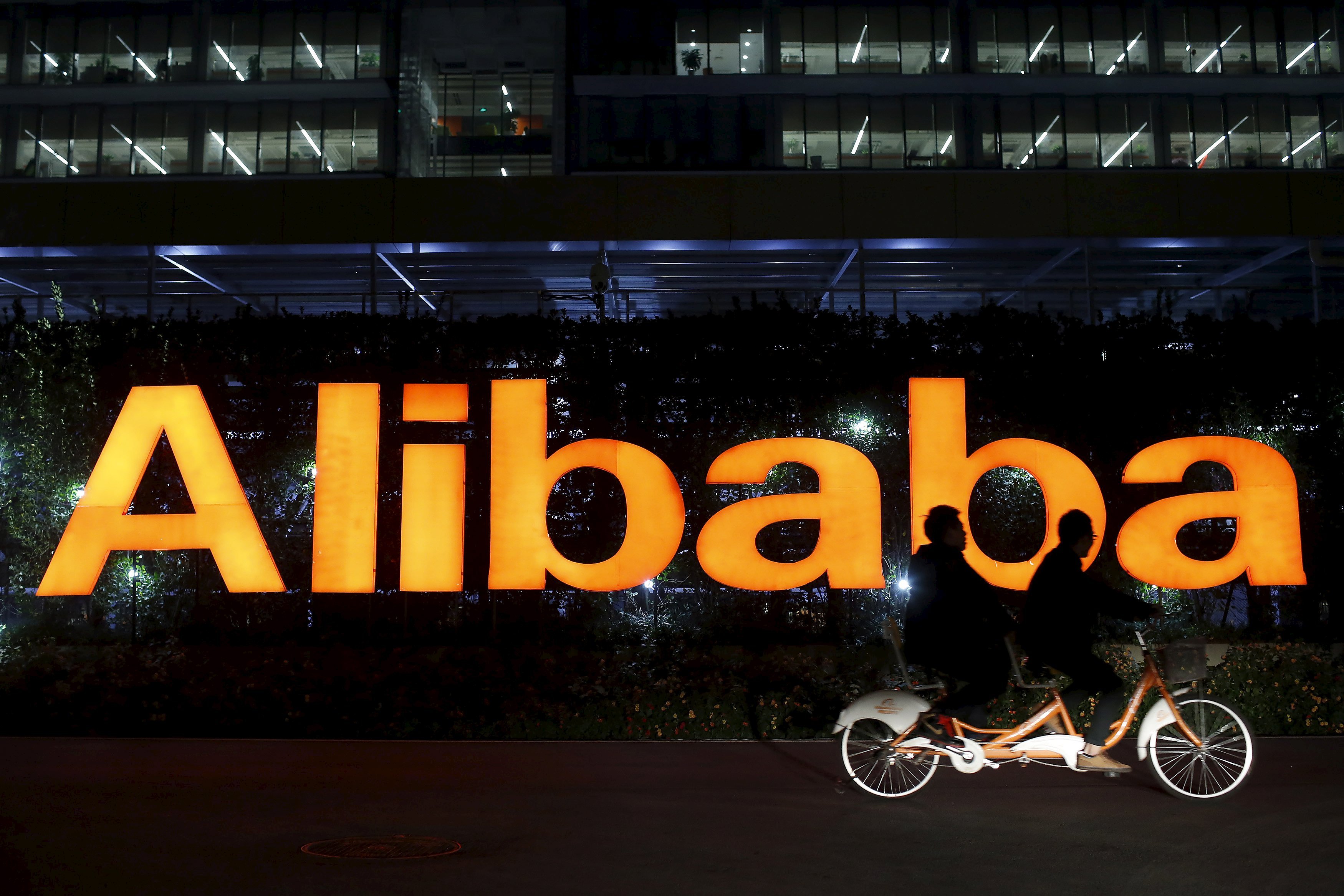 People ride a tandem bike past Alibaba Group's headquarters in China as Ali Pictures, a unit of the e-commerce giant, will raise HK$12.11 billion for media investment opportunities. Photo: Reuters