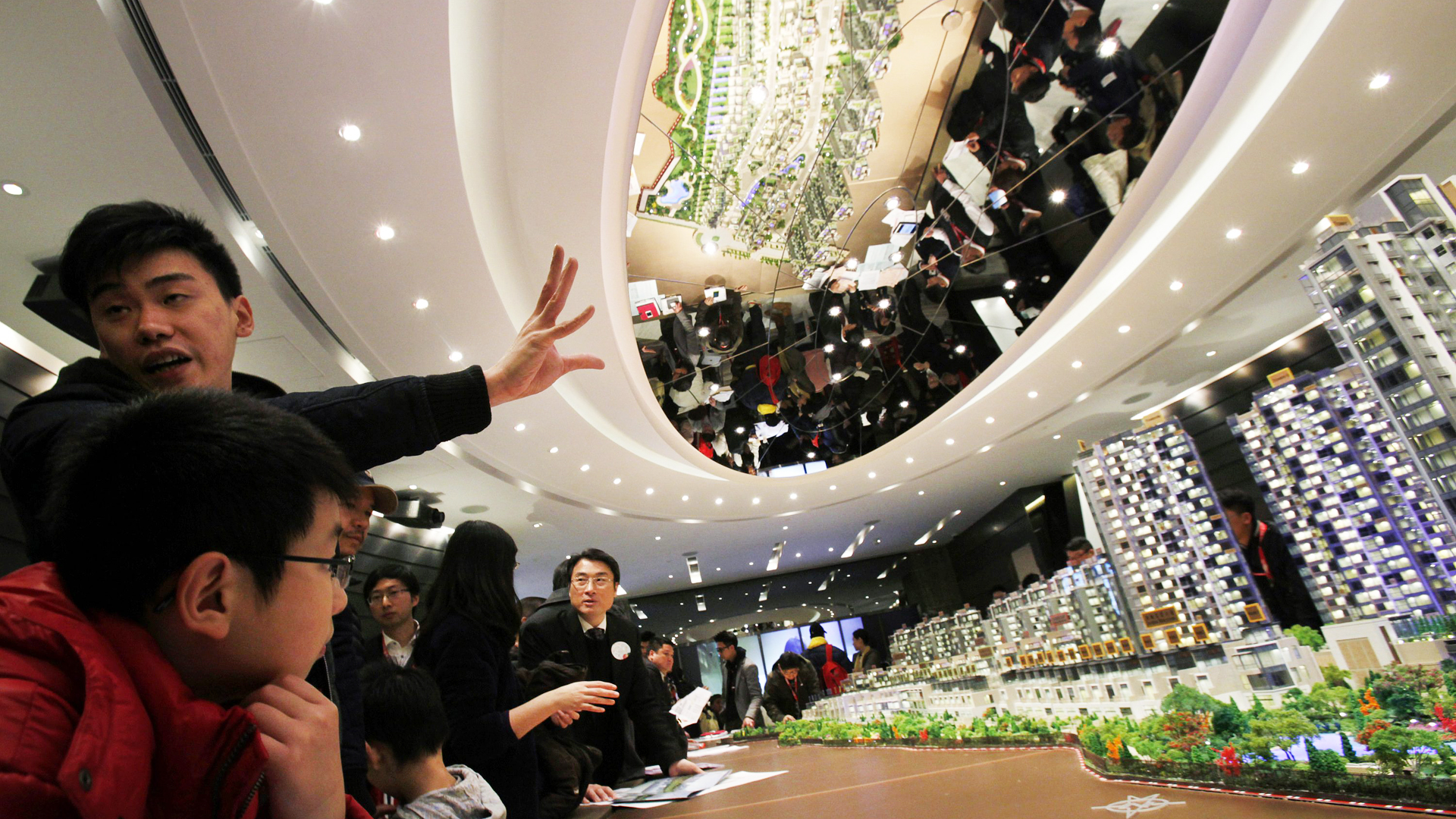 A sales agent speaks to potential buyers in front of a model of Riva, one of the latest developments by Sun Hung Kai Properties, in Hong Kong in 2014. Photo: Reuters