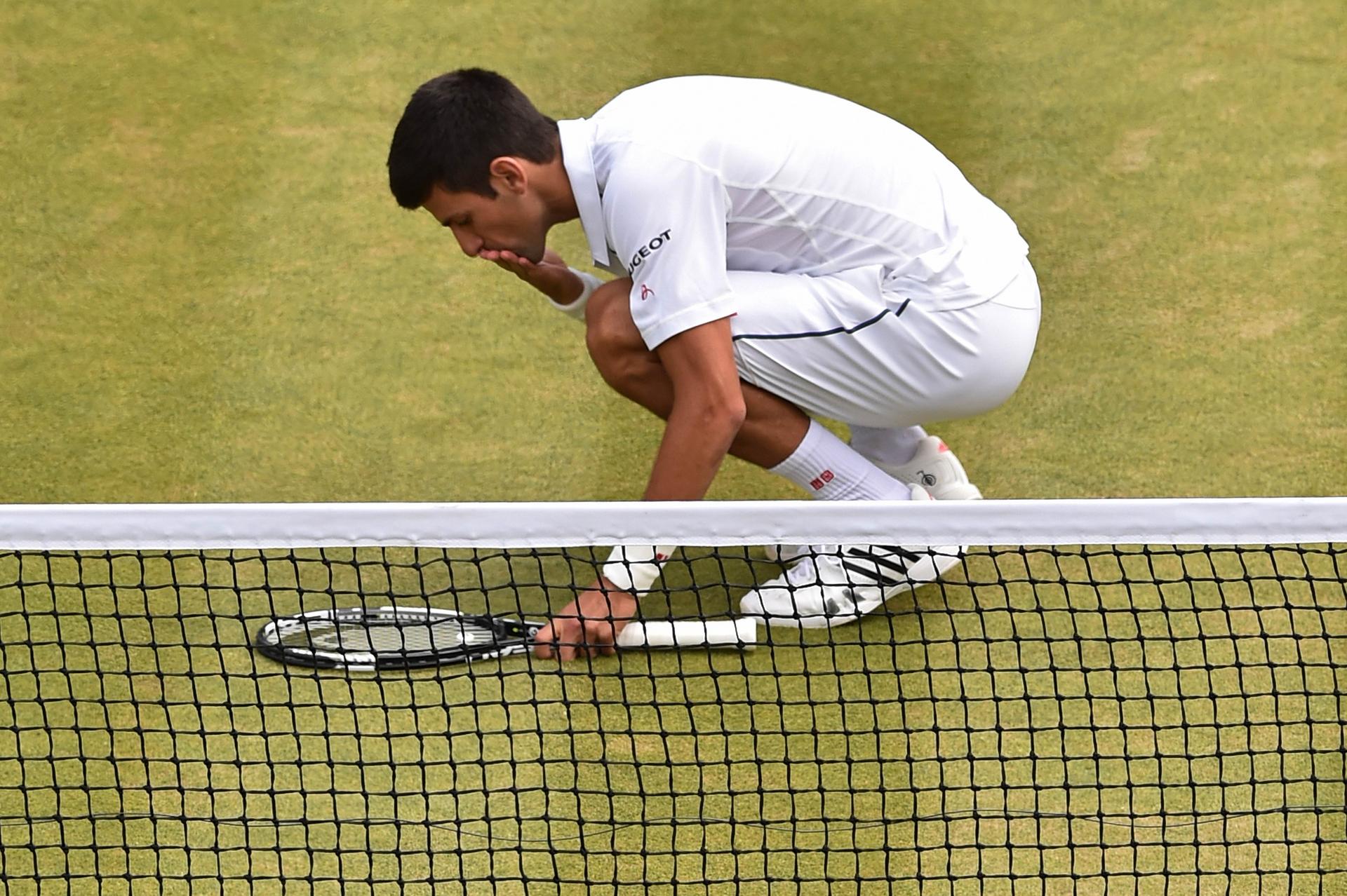 A relieved Novak Djokovic kisses the court after beating South Africa's Kevin Anderson yesterday in five sets. Photo: AFP