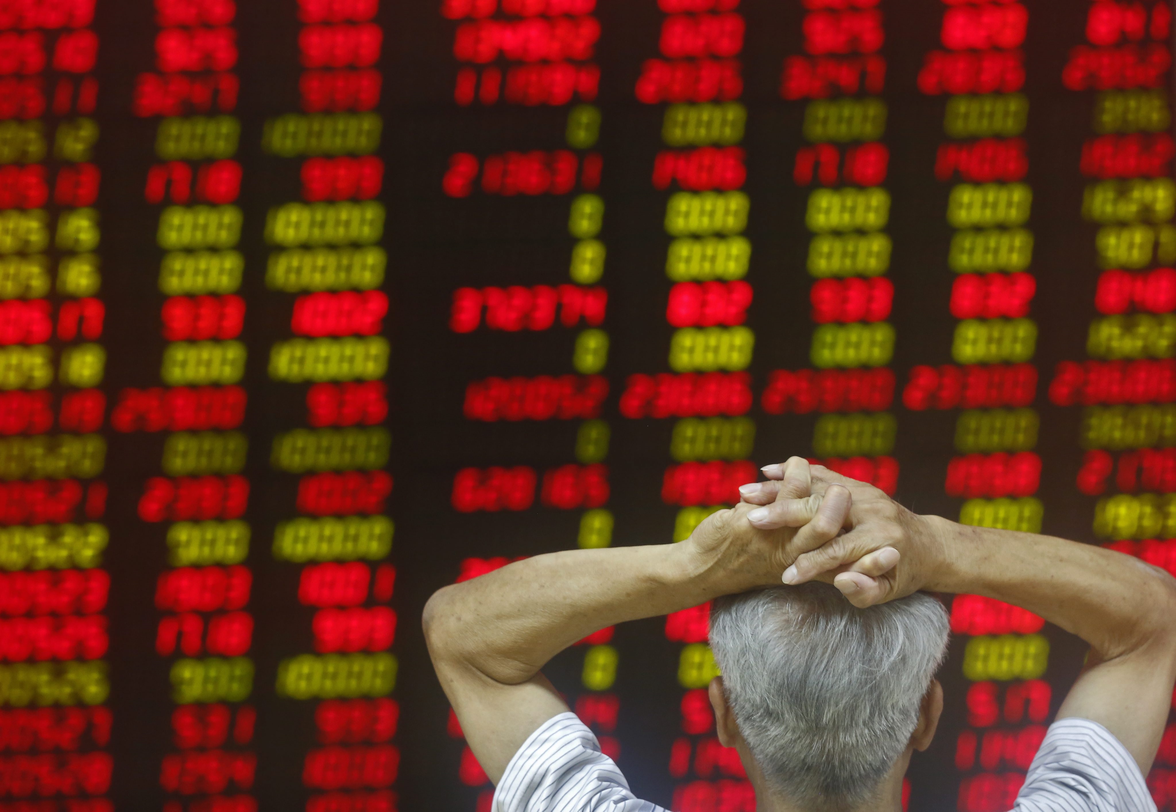A Chinese investor looks at an electronic screen showing market movements at a securities brokerage house in Beijing. Photo: EPA