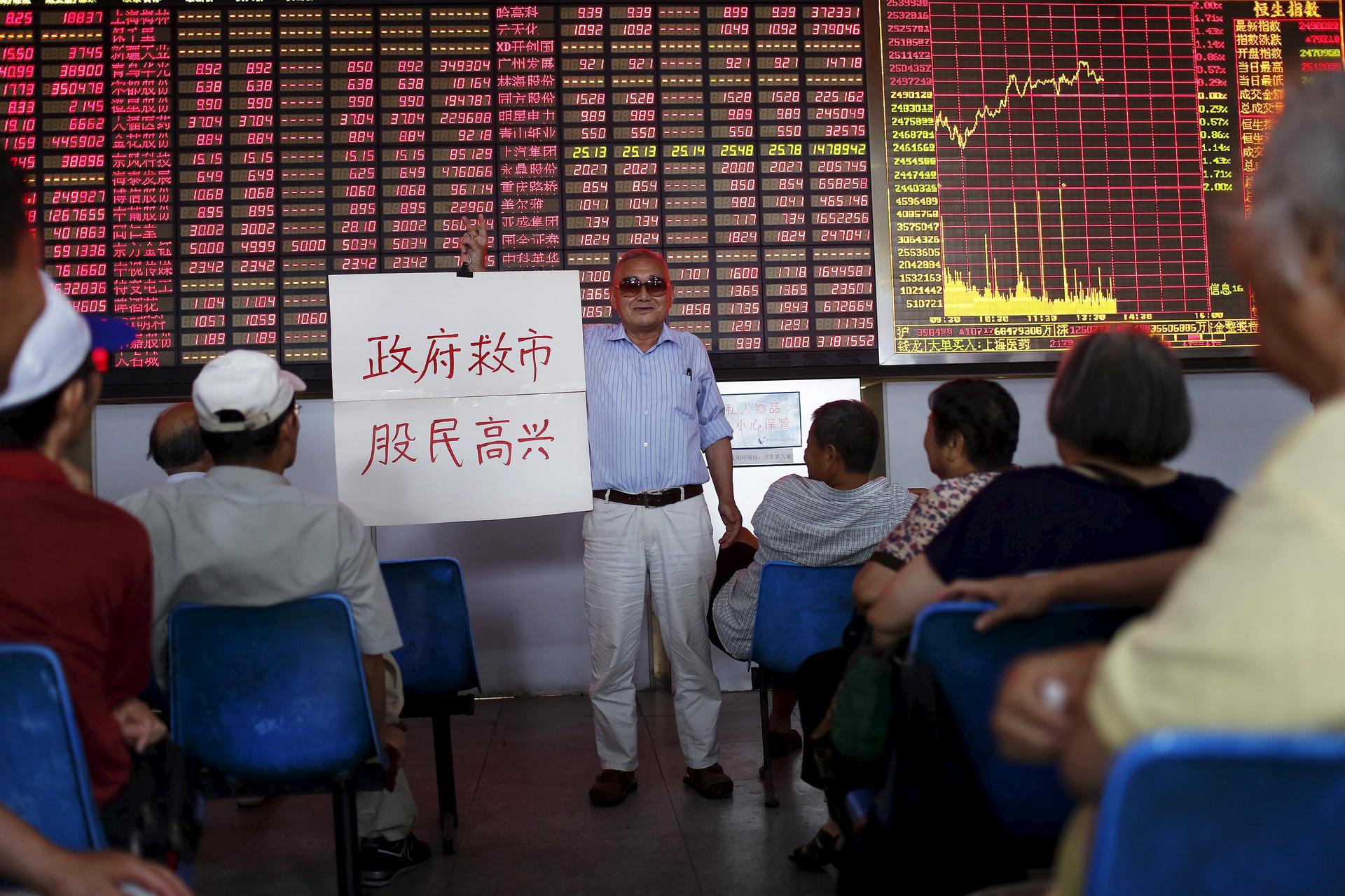 An investor holds a board saying "government saves the market so that investors will be happy" at a stockbroking firm in Shanghai. Photo: Reuters