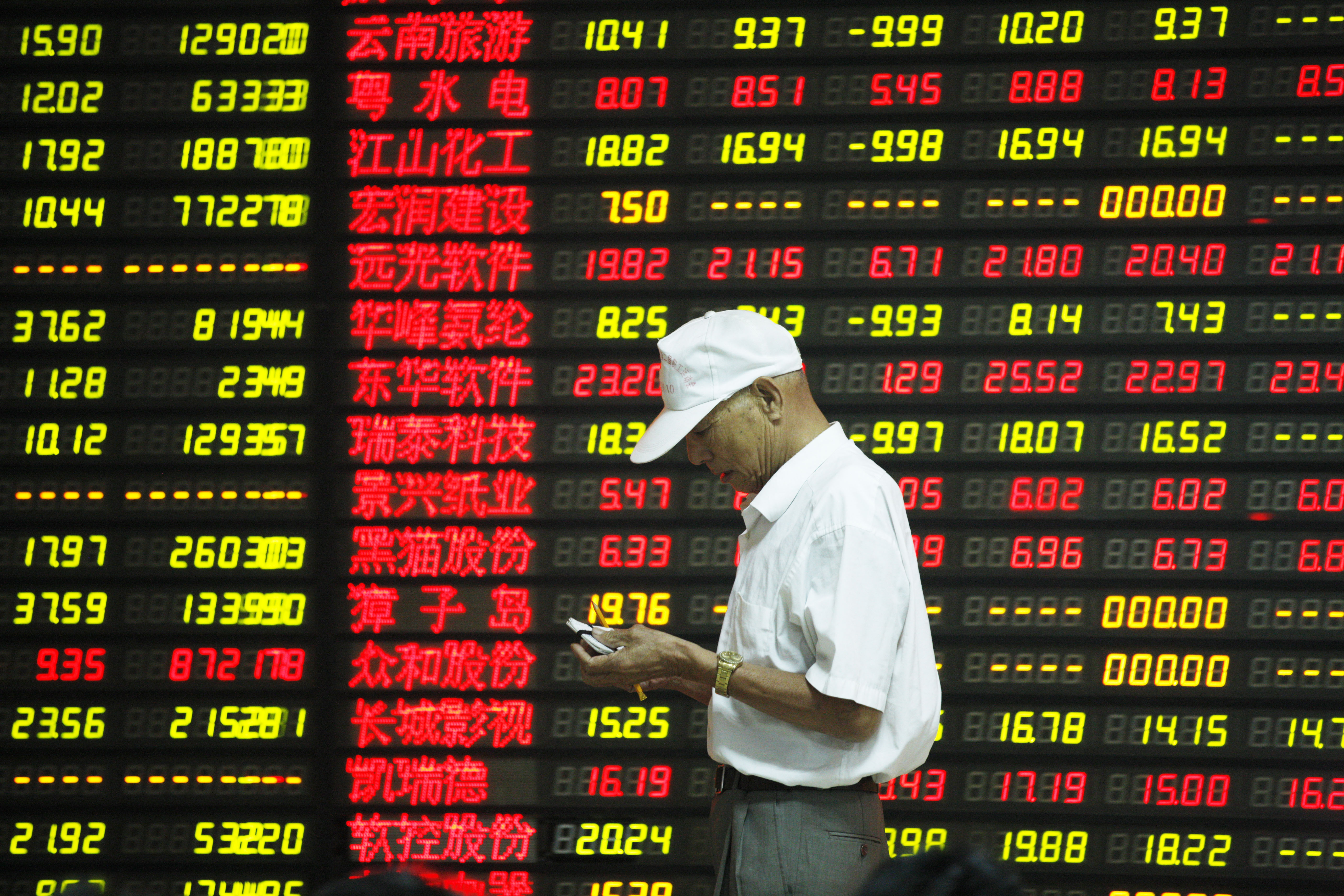 An investor in China is framed by an electronic board showing stock prices in the country's volatile equity markets. Photo: Xinhua