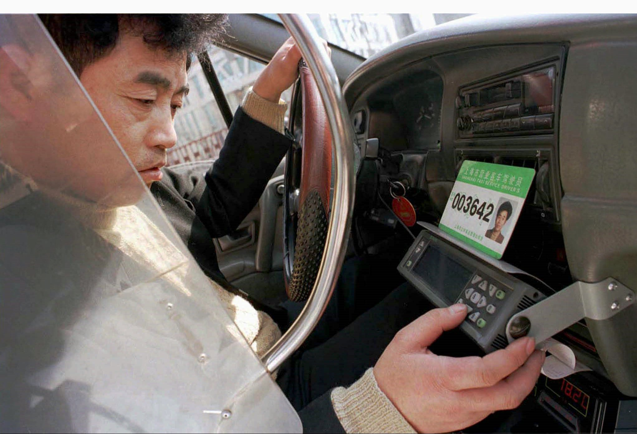 A Shanghai cab driver works on his GPS machine as taxis complain about the competition from outfits like Uber. Photo: Reuters