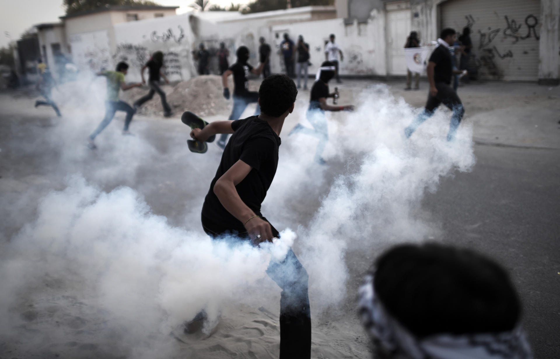 A Bahraini protestor throws a tear gas canister back at riot police during clashes in April last year.