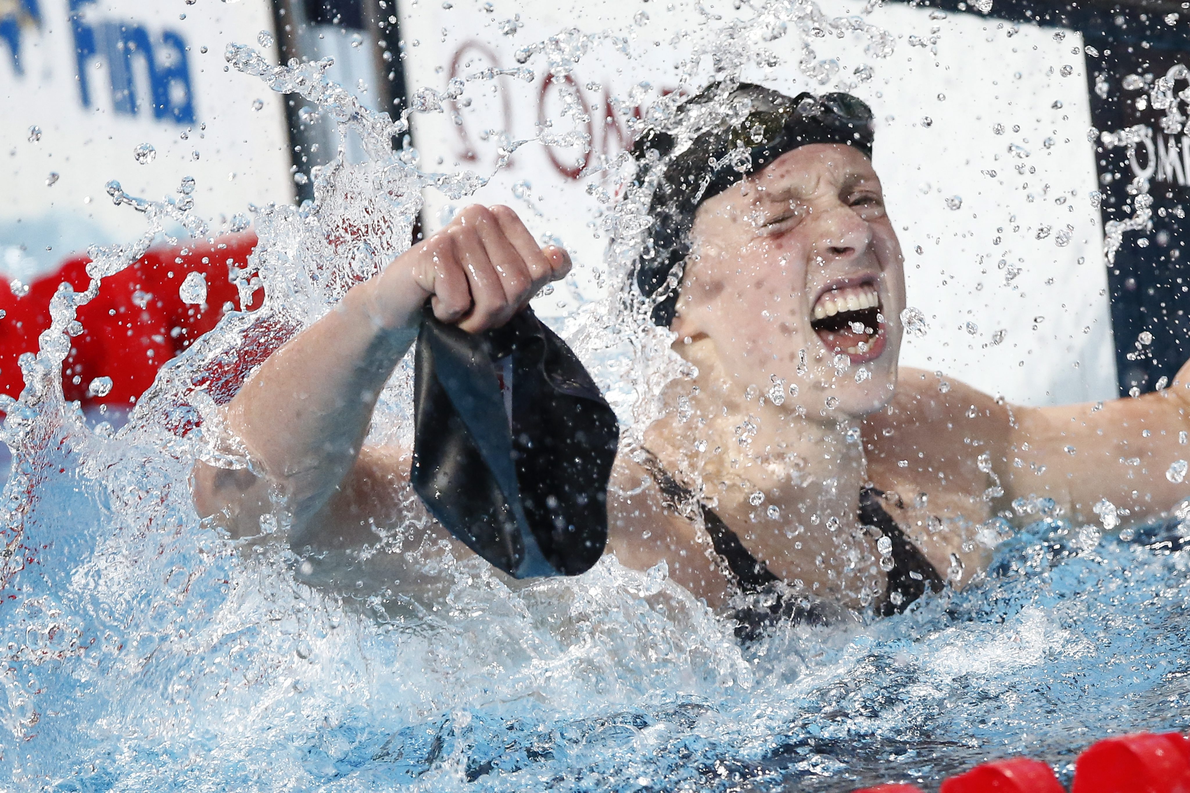 Katie Ledecky pulls off one of her swim caps after winning her fifth gold and clocking a world record in the women's 800m freestyle final. Photo: EPA