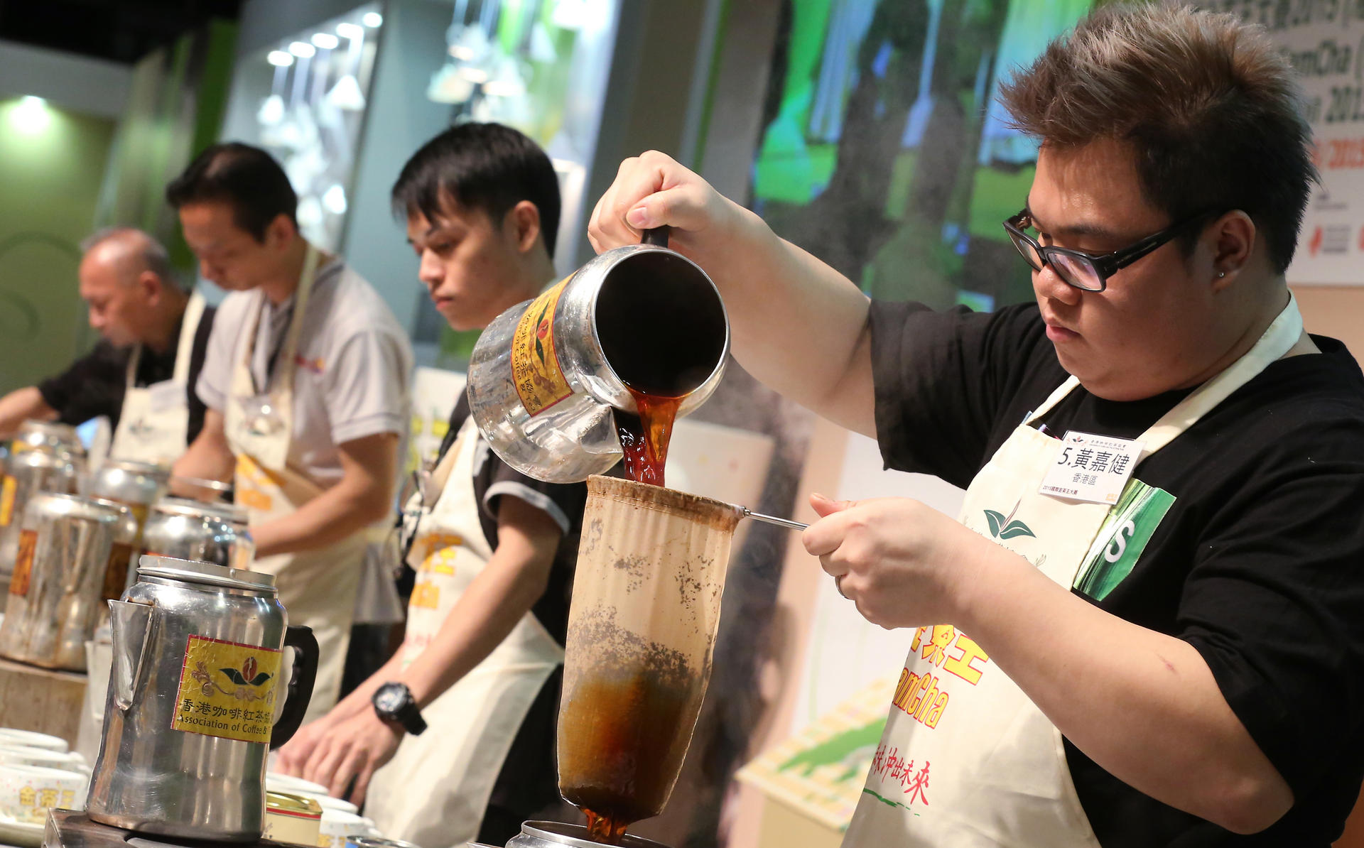 Wong Ka-kin (right) shows off his skills during the contest to make the best cup of Hong Kong-style milk tea. Photo: Edward Wong