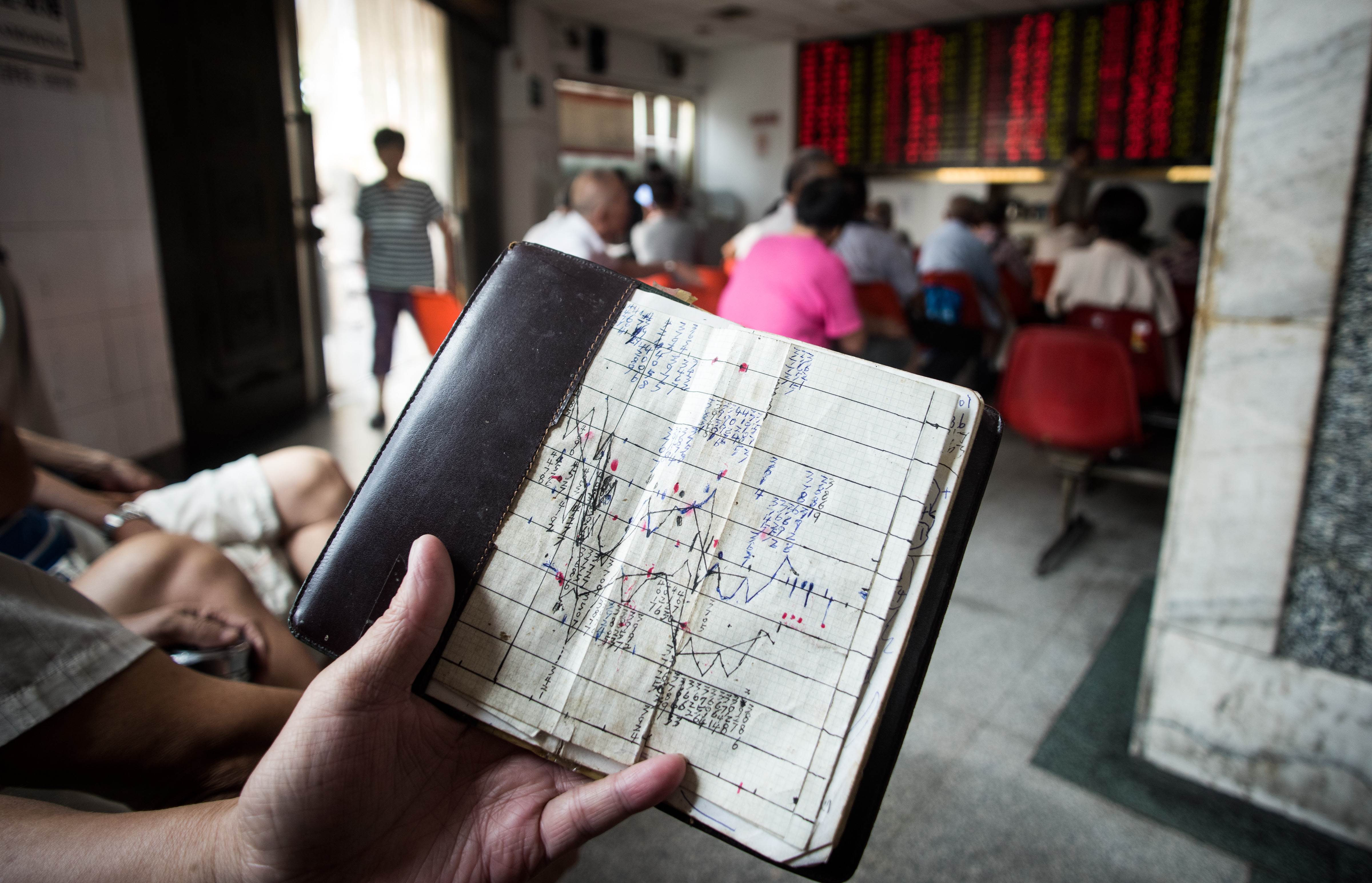 An investor holds a notebook showing stock market movements, as he sits at a brokerage house in Shanghai. Photo: AFP