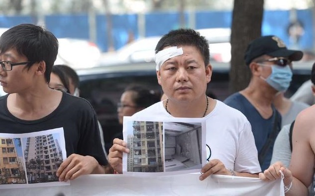 Frustrated owners from the Qihang Jiayuan residential compound demonstrate outside a press briefing. File Photo