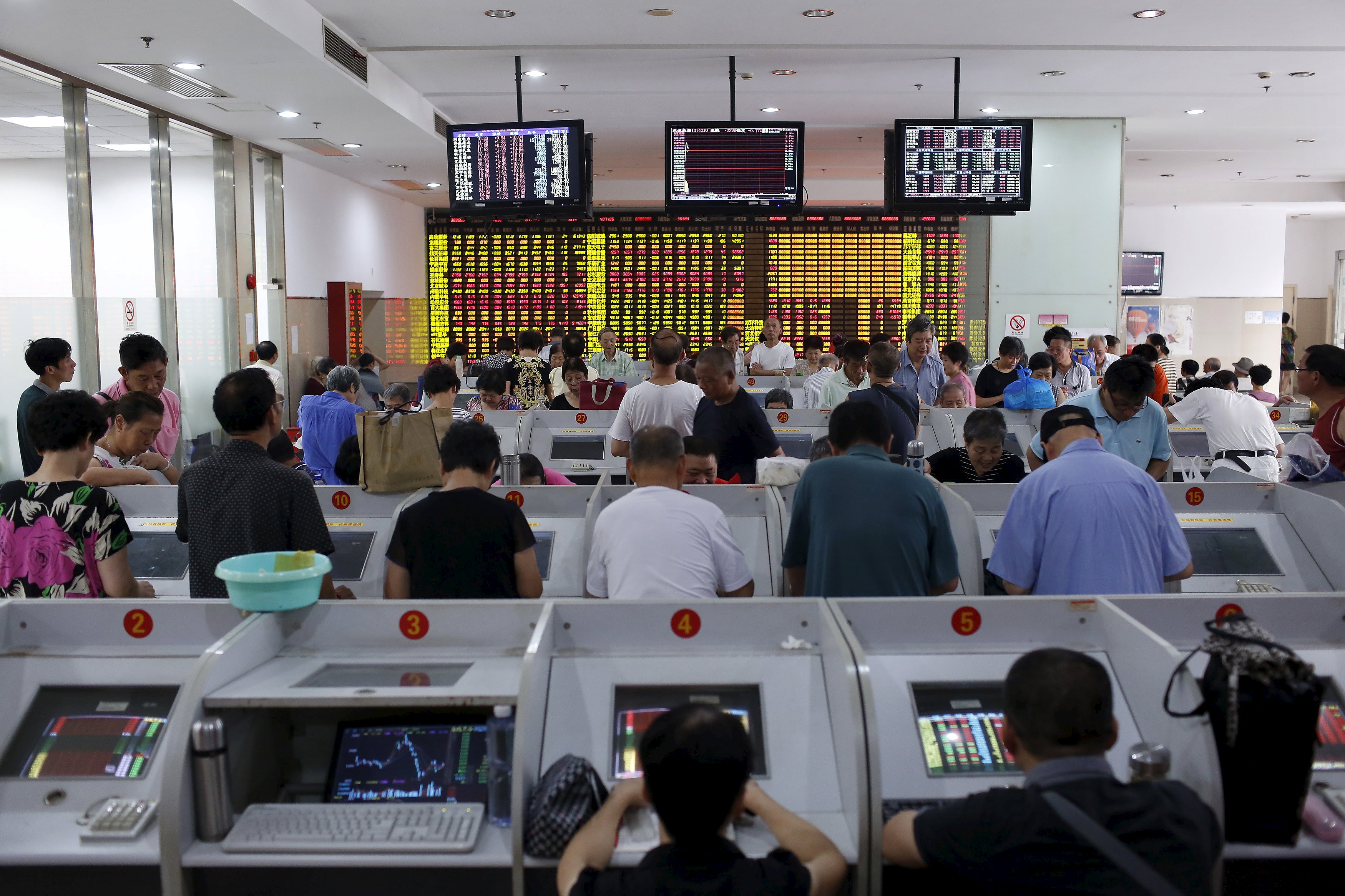 Dozens of investors study their computer screens at a stock brokerage in ShanghaI, China. Photo: Reuters