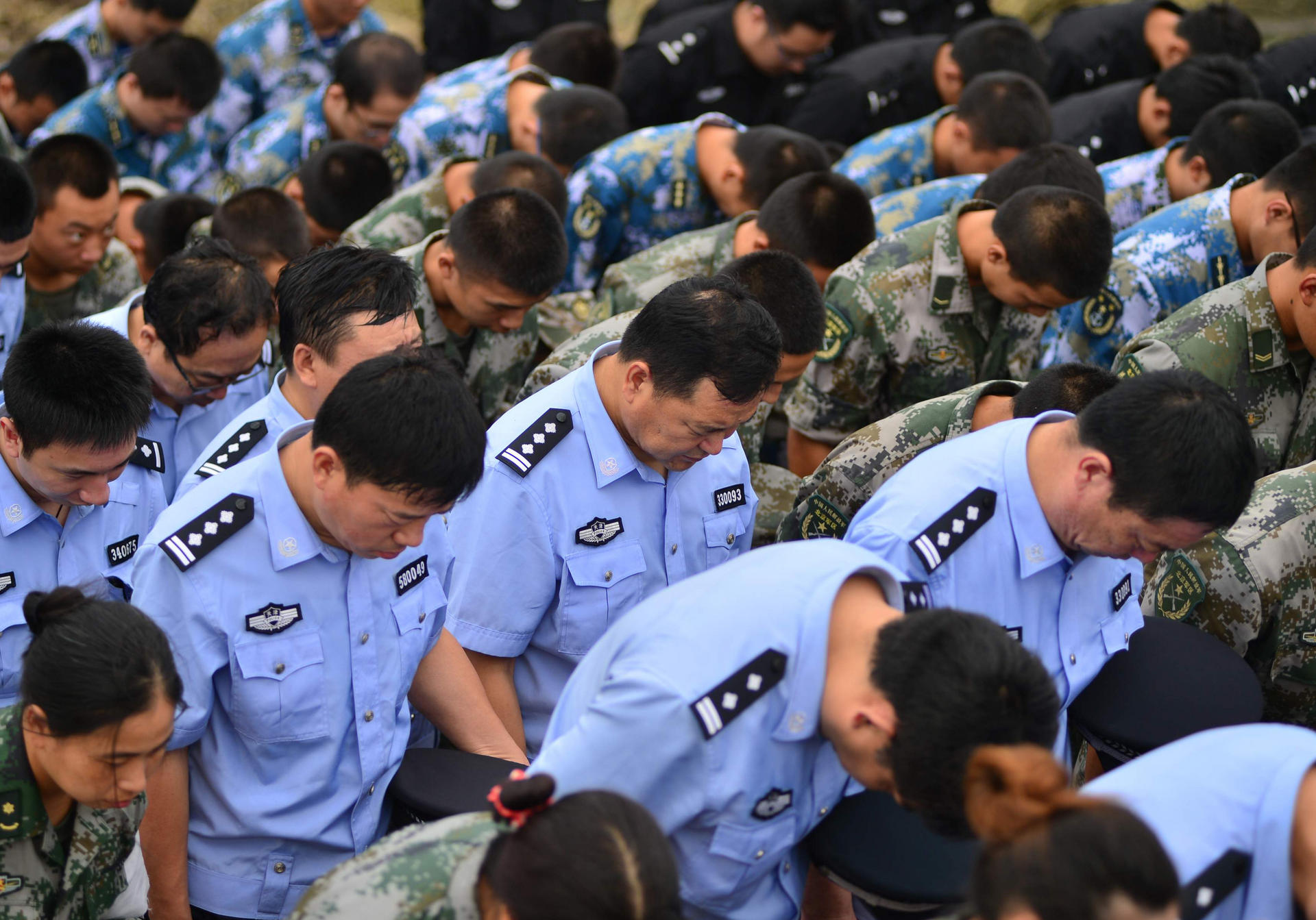 Soldiers, police officers and paramilitary policy bow their heads at a ceremony on Tuesday to mourn the victims of Tianjin's explosions. Photo: Xinhua