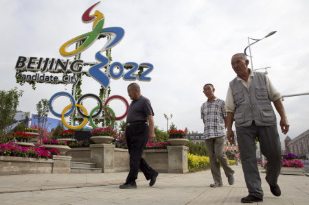 People walk past the Olympic bid logo in Chongli county, Hebei, where Nordic skiing and ski jumping events will be held. Photo: AP