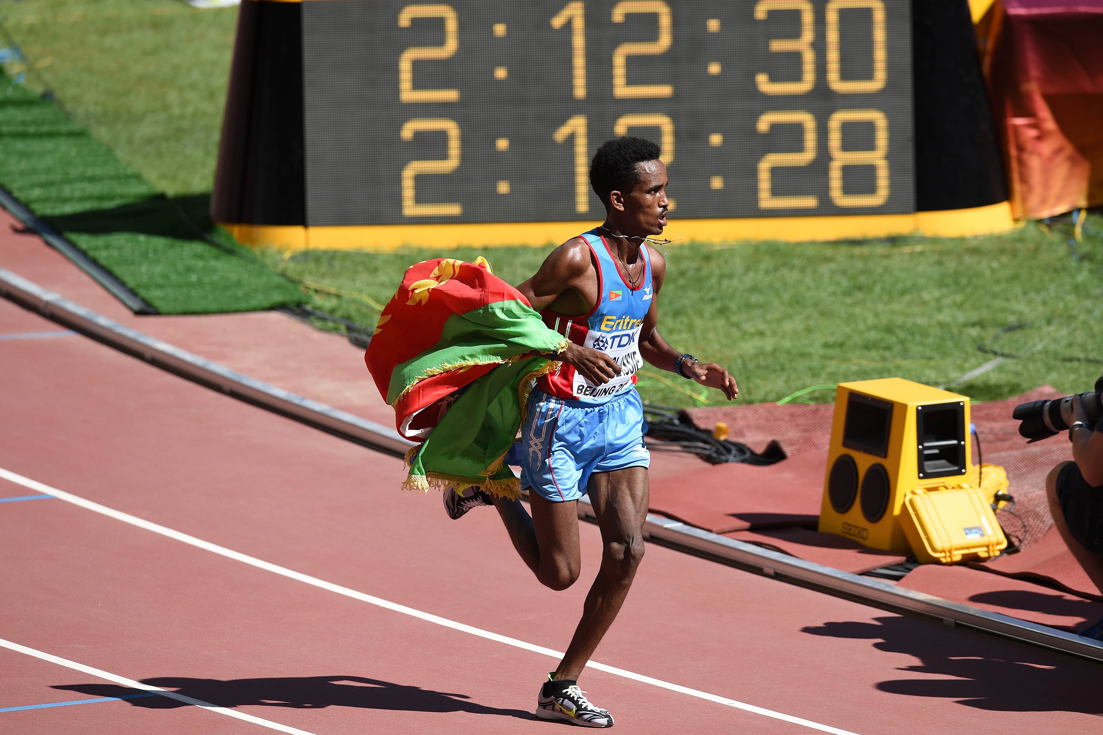 Wrapped in the Eritrean flag, Ghirmay Ghebreslassie races to victory in the men's marathon at the "Bird's Nest" National Stadium in Beijing. Photo: AFP