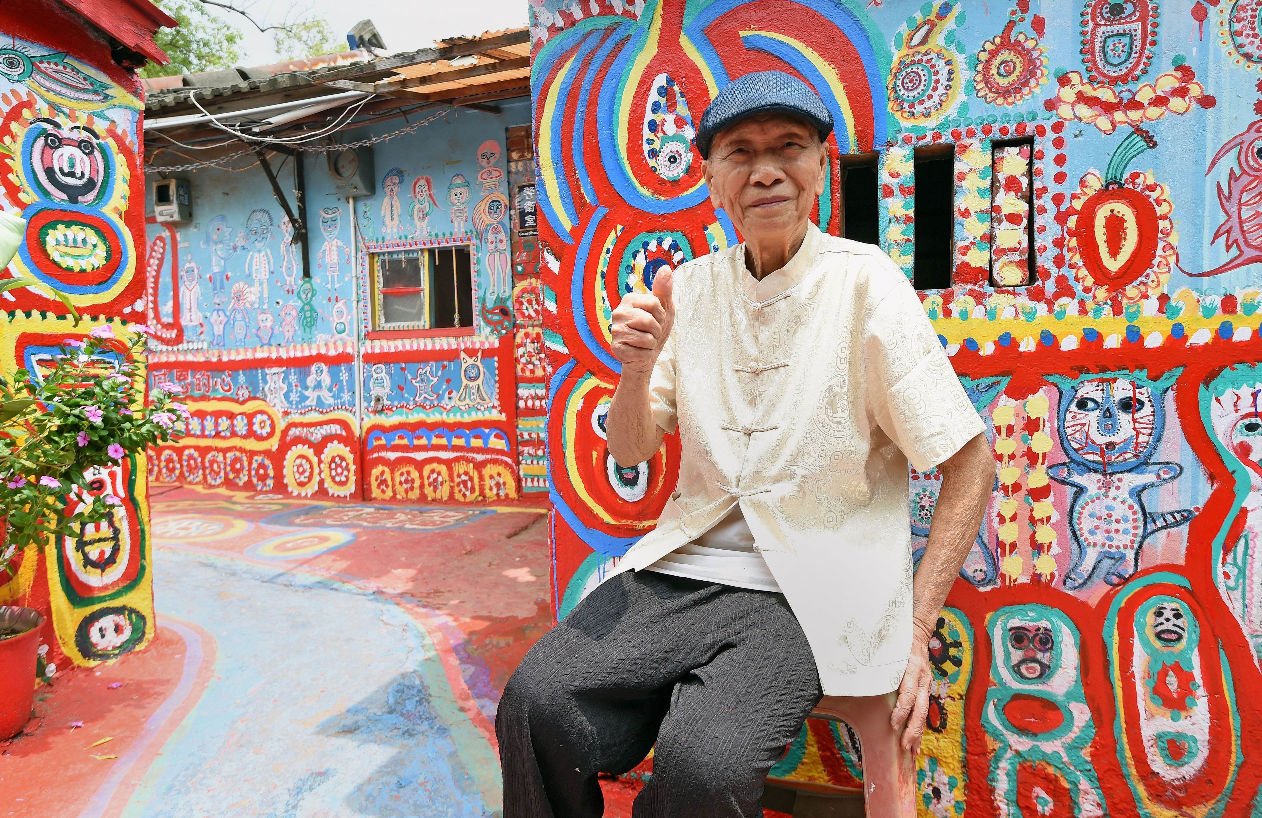 Huang Yung-fu posing for a photo next to his artwork in the Rainbow Village. Photo: AFP