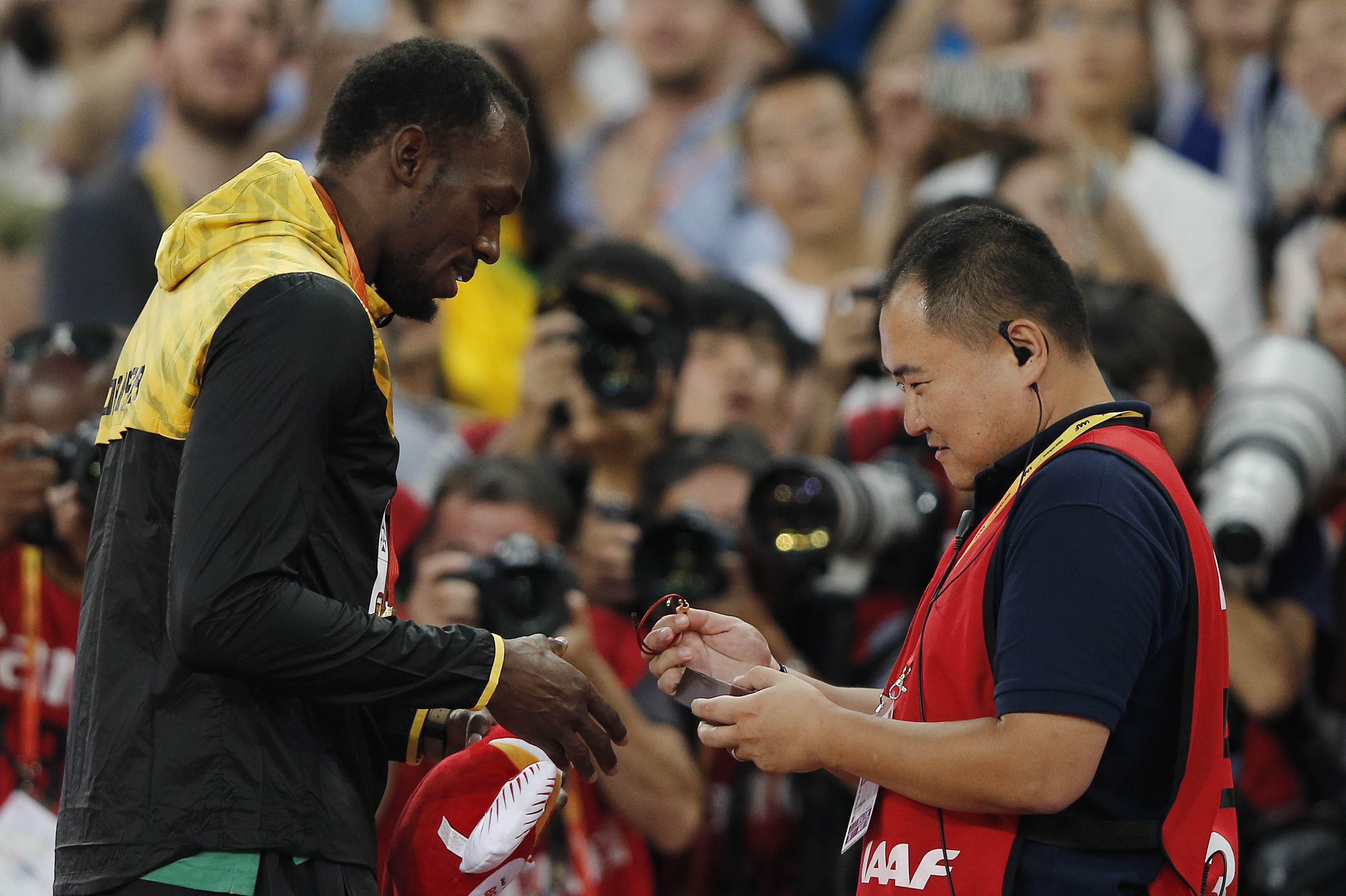 CCTV journalist Song Tao presents Jamaica's gold medallist Usain Bolt with a gift during the victory ceremony for the men's 200m. Photo: AFP 