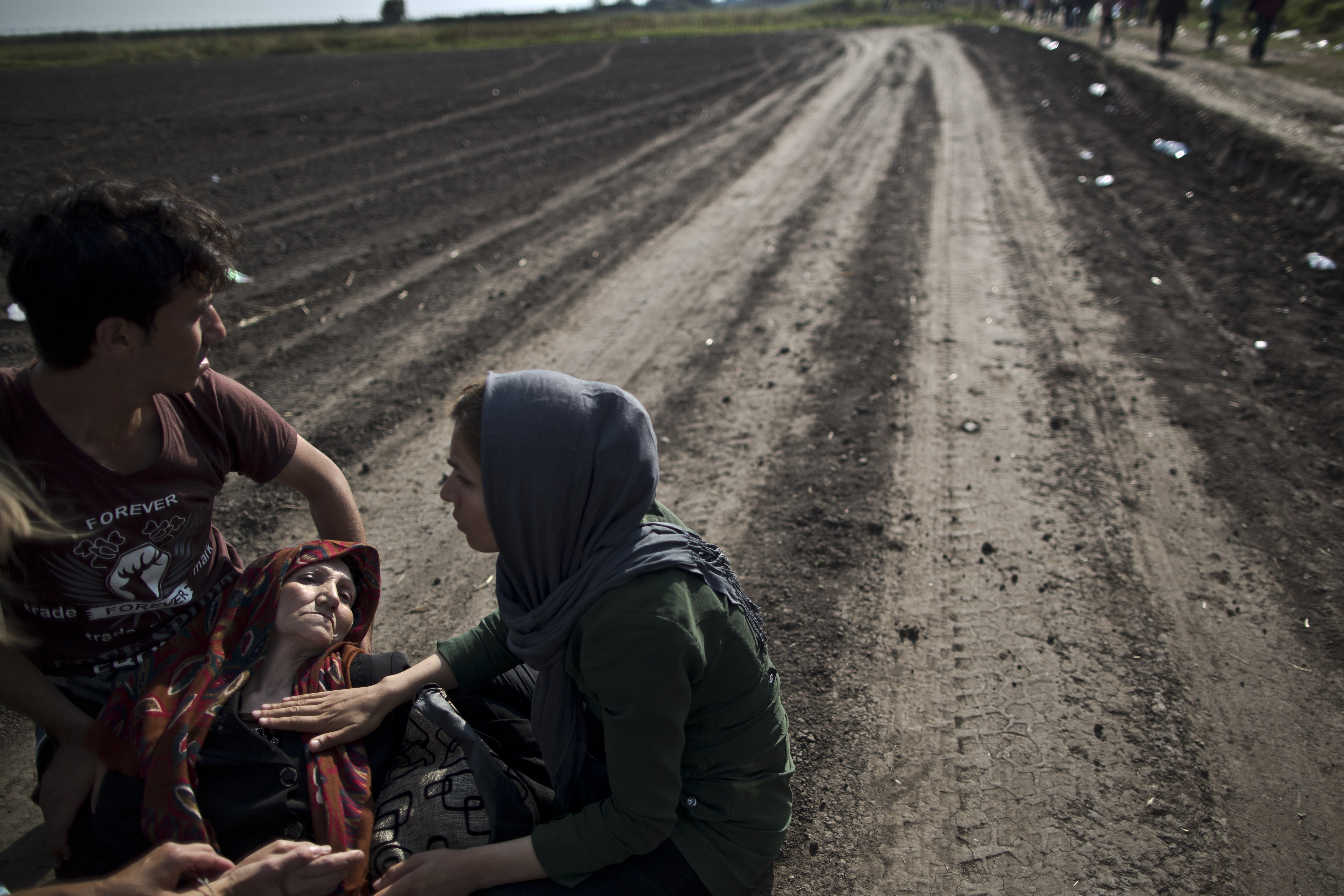 An Afghan refugee is helped by her son, daughter and a volunteering doctor after collapsing while crossing the border between Serbia and Hungary. Photo: AP