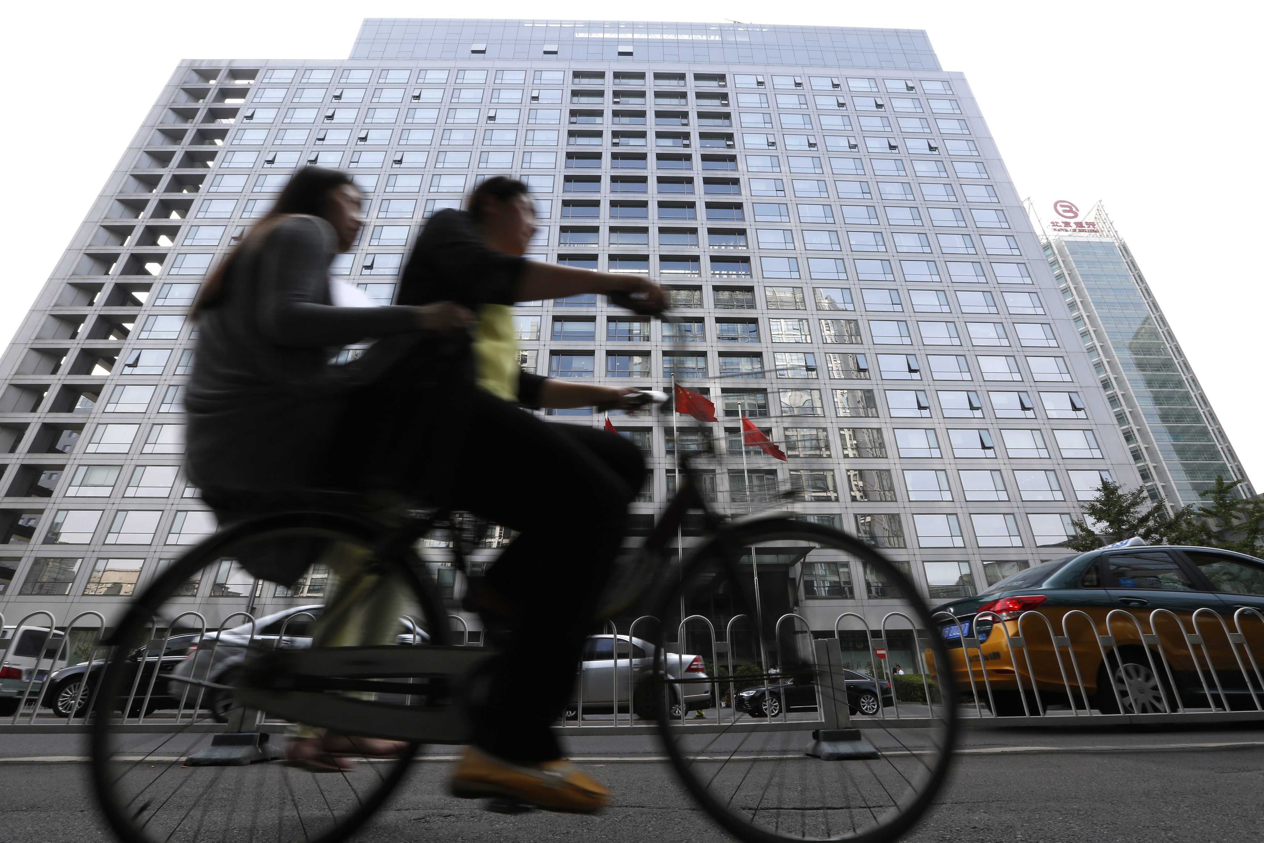 Cyclists pedal past the China Securities Regulatory Commission building in Beijing. Photo: EPA