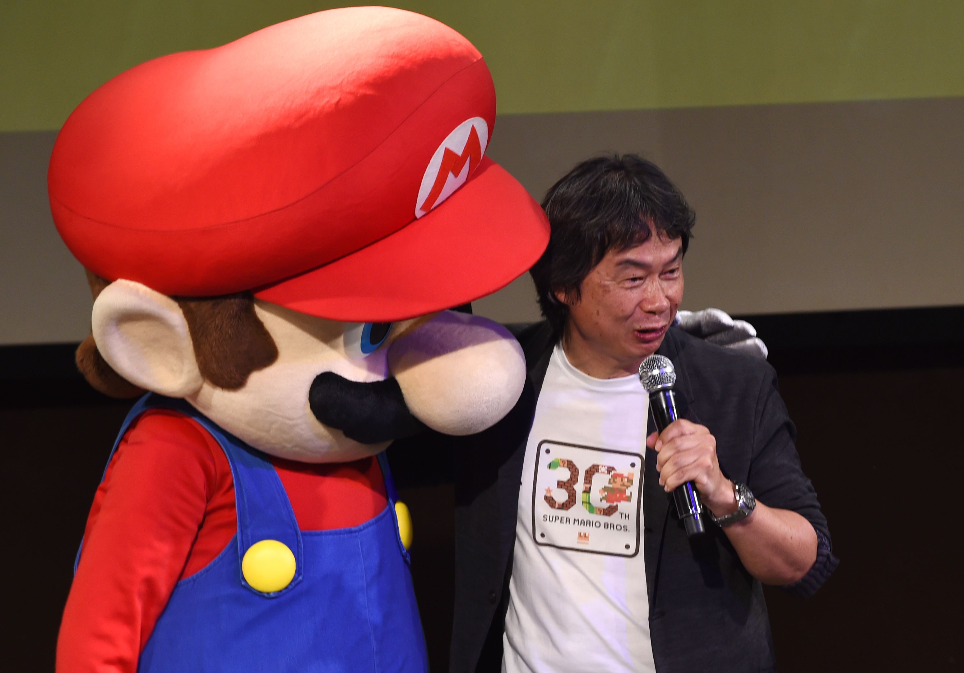 Nintendo game creator Shigeru Miyamoto (poses with his character Super Mario  during a live performance of the most well-known Mario music to mark the game's 30th anniversary in Tokyo. Photo: AFP