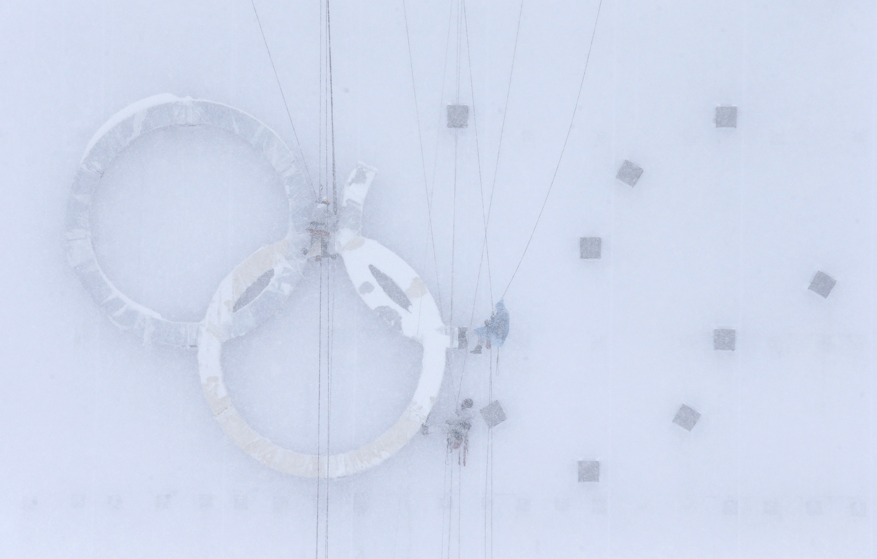 People work on the Olympic rings during heavy snow at one of the Games venues ahead of the 2014 Sochi Olympics. Photo: Reuters