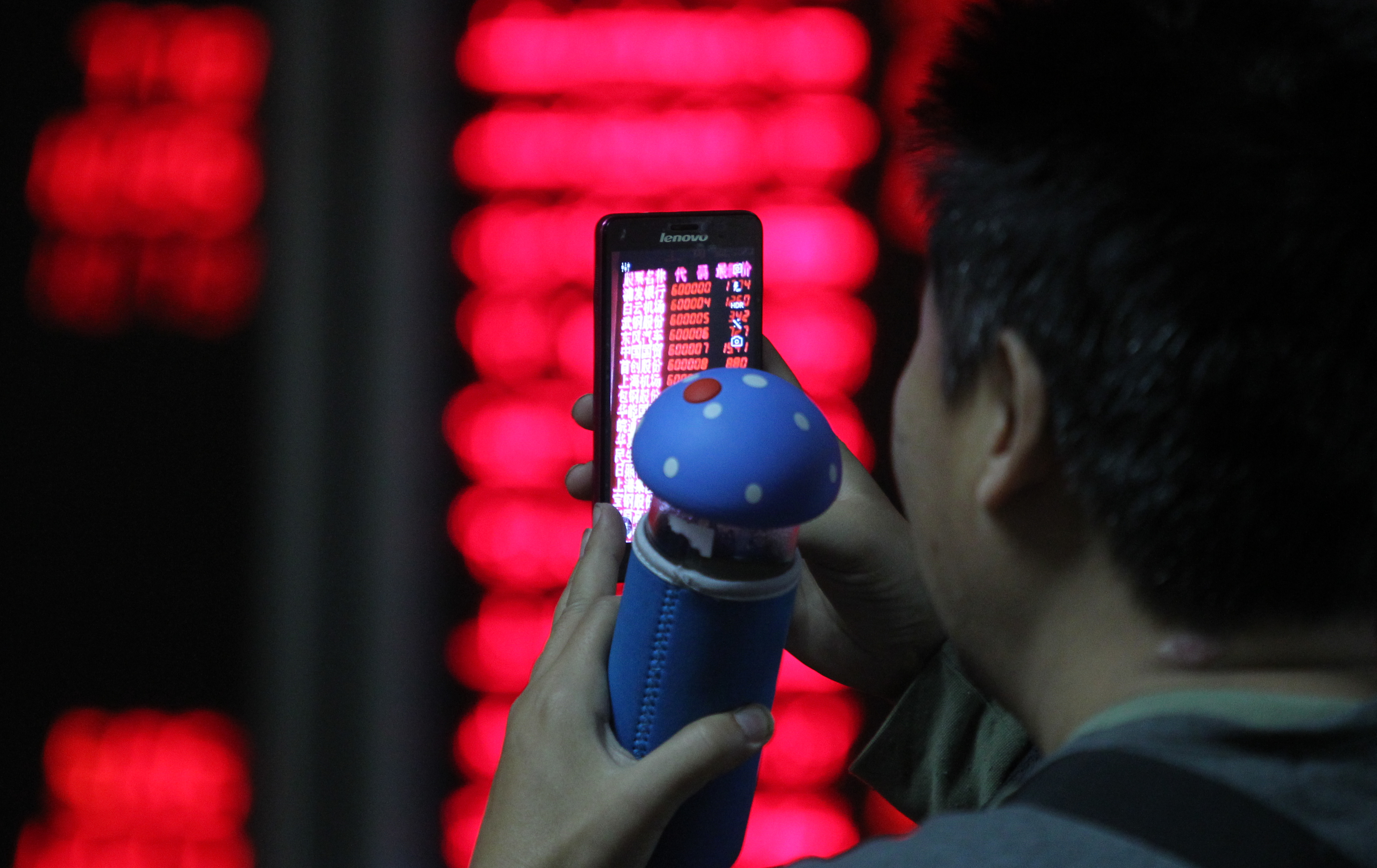 A Chinese investor takes a smartphone photo of electronic displays showing stock prices in a brokerage house in Beijing. Photo: AP