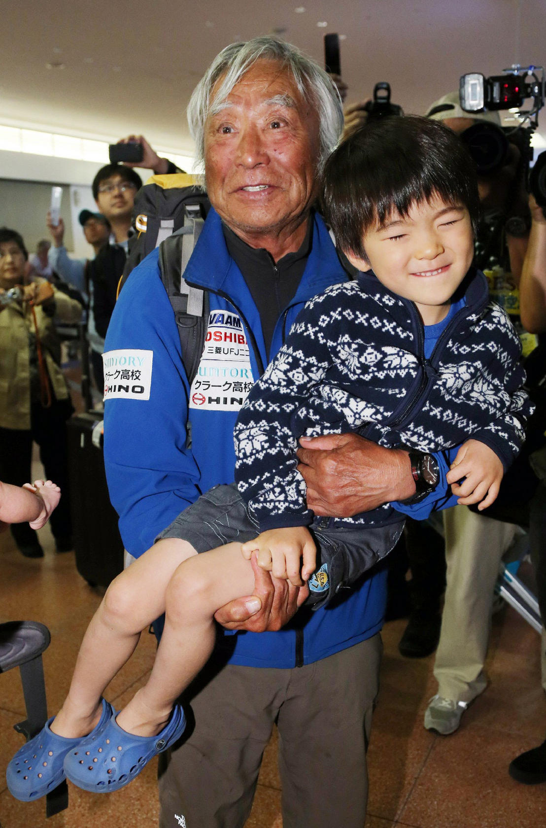 Yuichiro Miura holds his grandson upon his arrival in Tokyo on May 29, 2013, after having scaled the world's highest mountain at the age of 80.