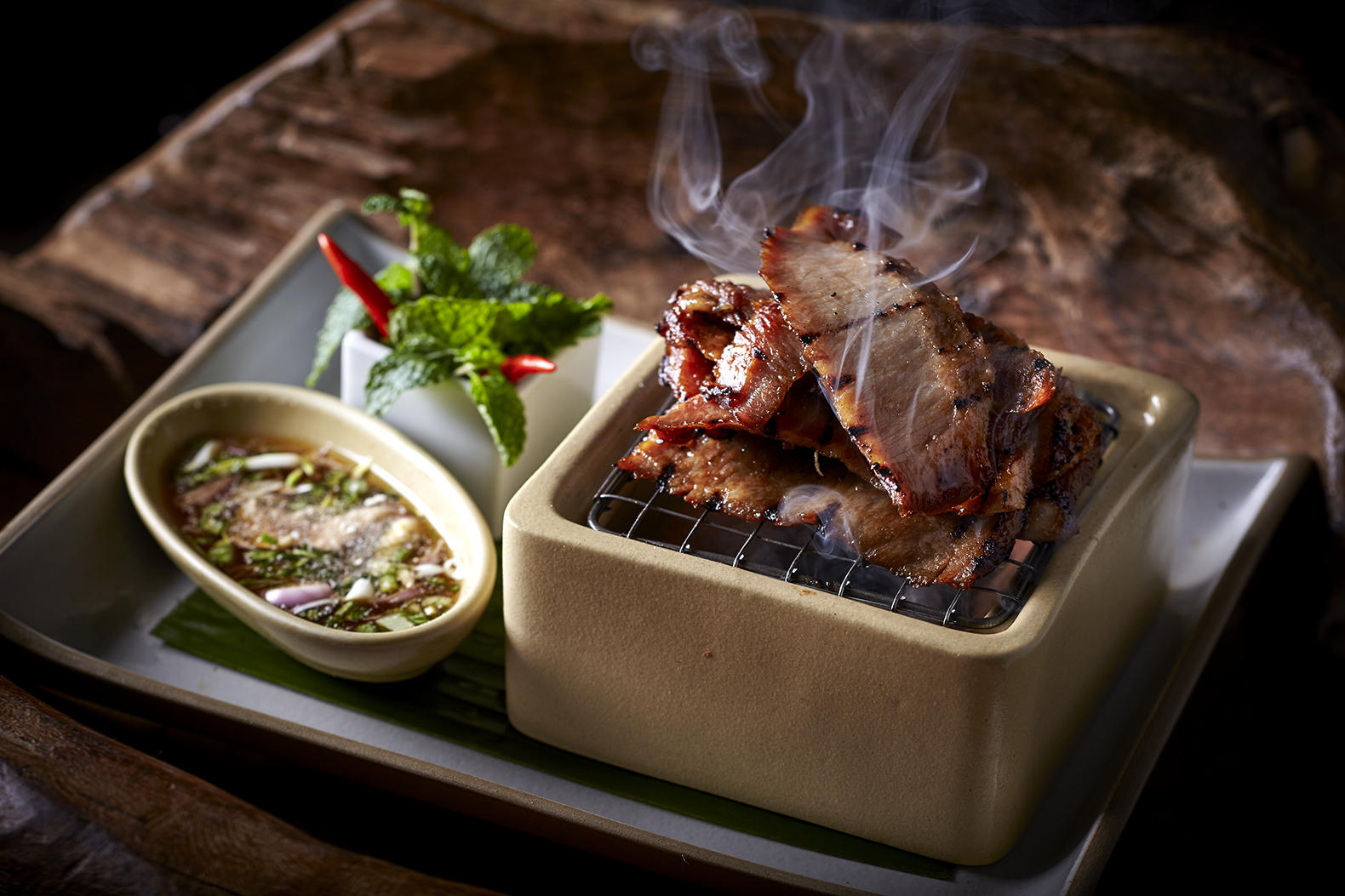 Grilled pork neck, served on a mini grill, comes with a flavoursome sauce.
