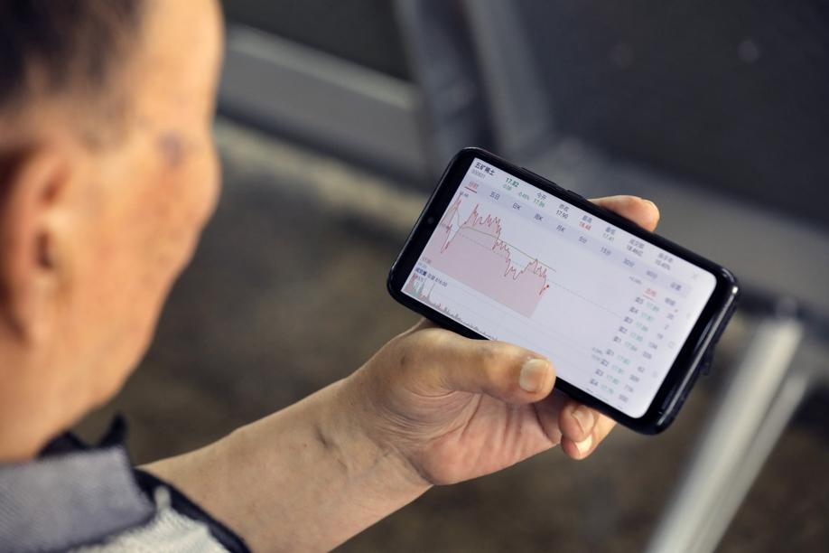 A Chinese investor uses a mobile phone to check a rare earths company's stock price at a securities brokerage house in Beijing. Photo: EPA-EFE