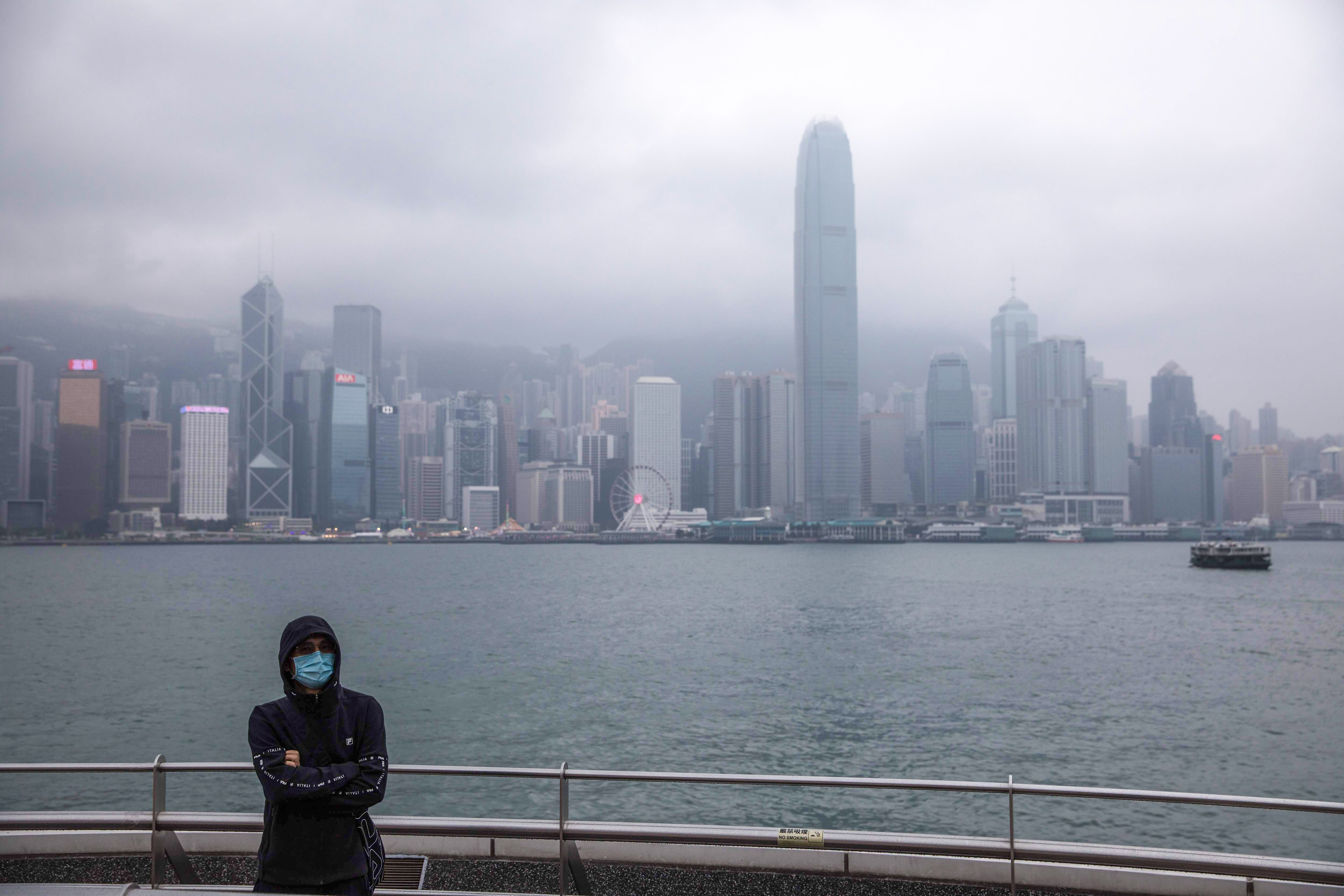 A man wearing a mask stands before the city skyline. World health authorities will meet today to decide whether to declare the rapidly spreading Wuhan coronavirus as a threat to global public health. Photo: AFP