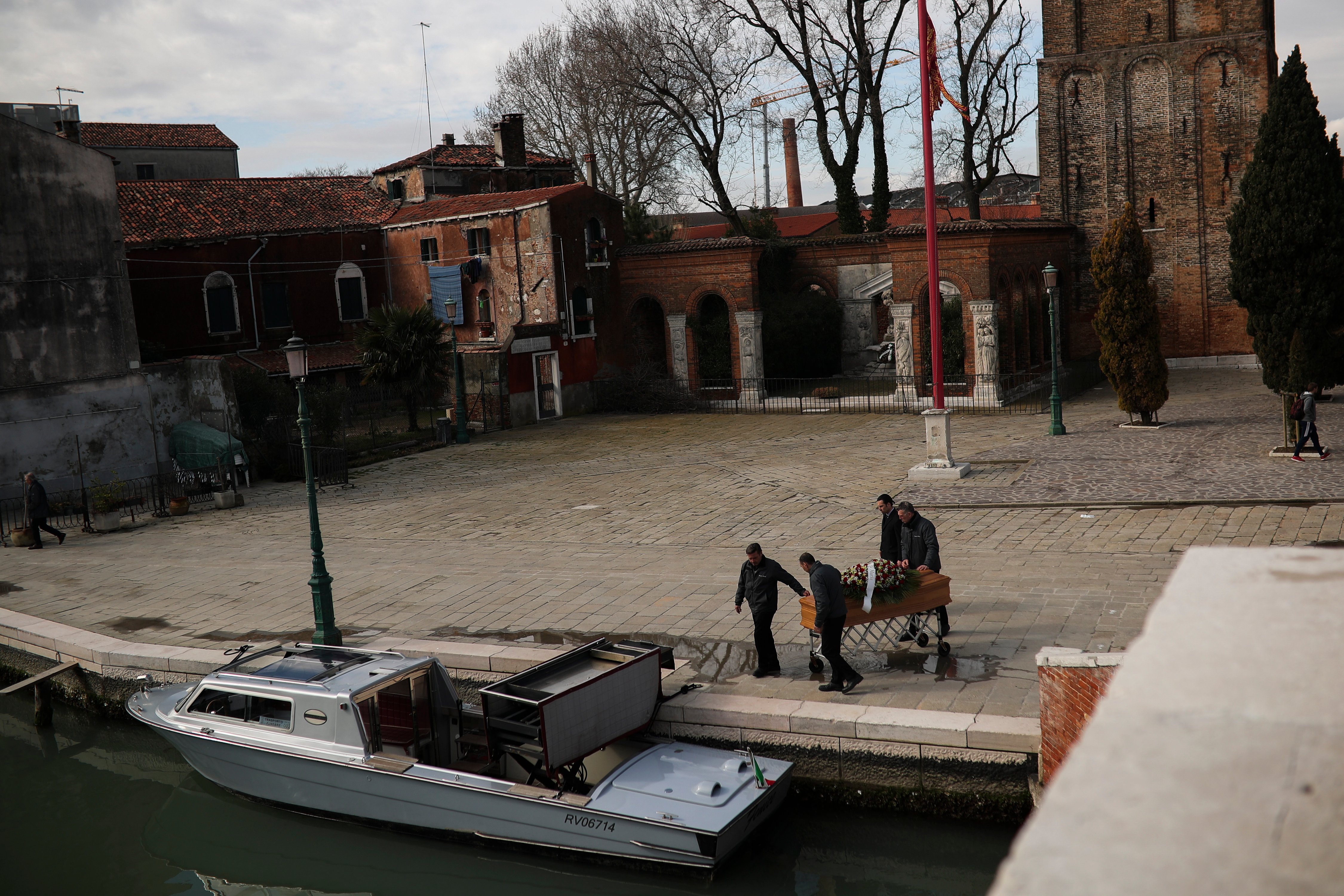 Funeral service workers push a coffin to place in a boat after a mass at the Murano island in Venice, Italy, on March 3, 2020. Photo: Associated Press 
