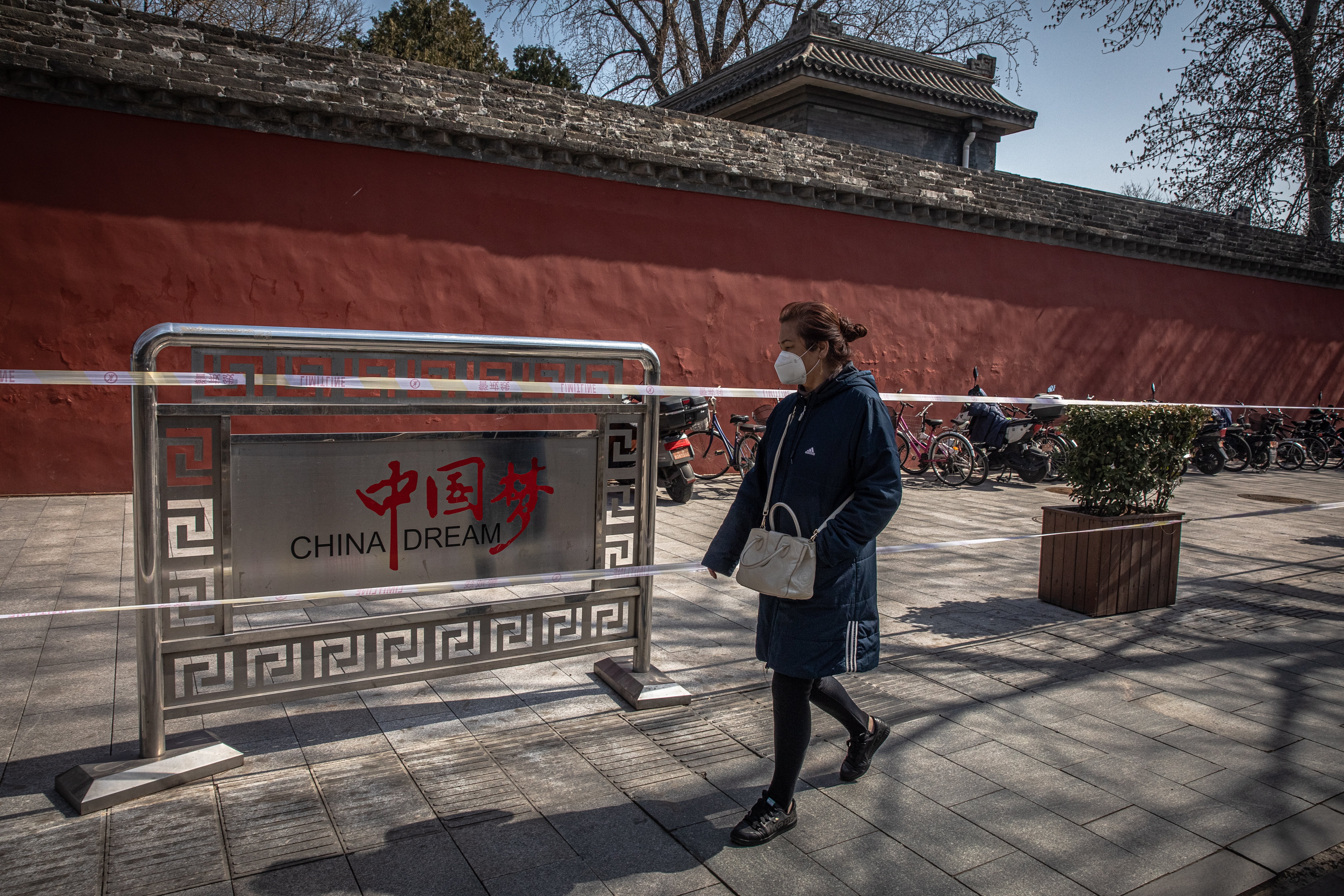 A woman walks past the security fence on a street in Beijing on March 11, 2020, as China tries to return to normalcy after being clobbered by the coronavirus. Photo: EPA-EFE
