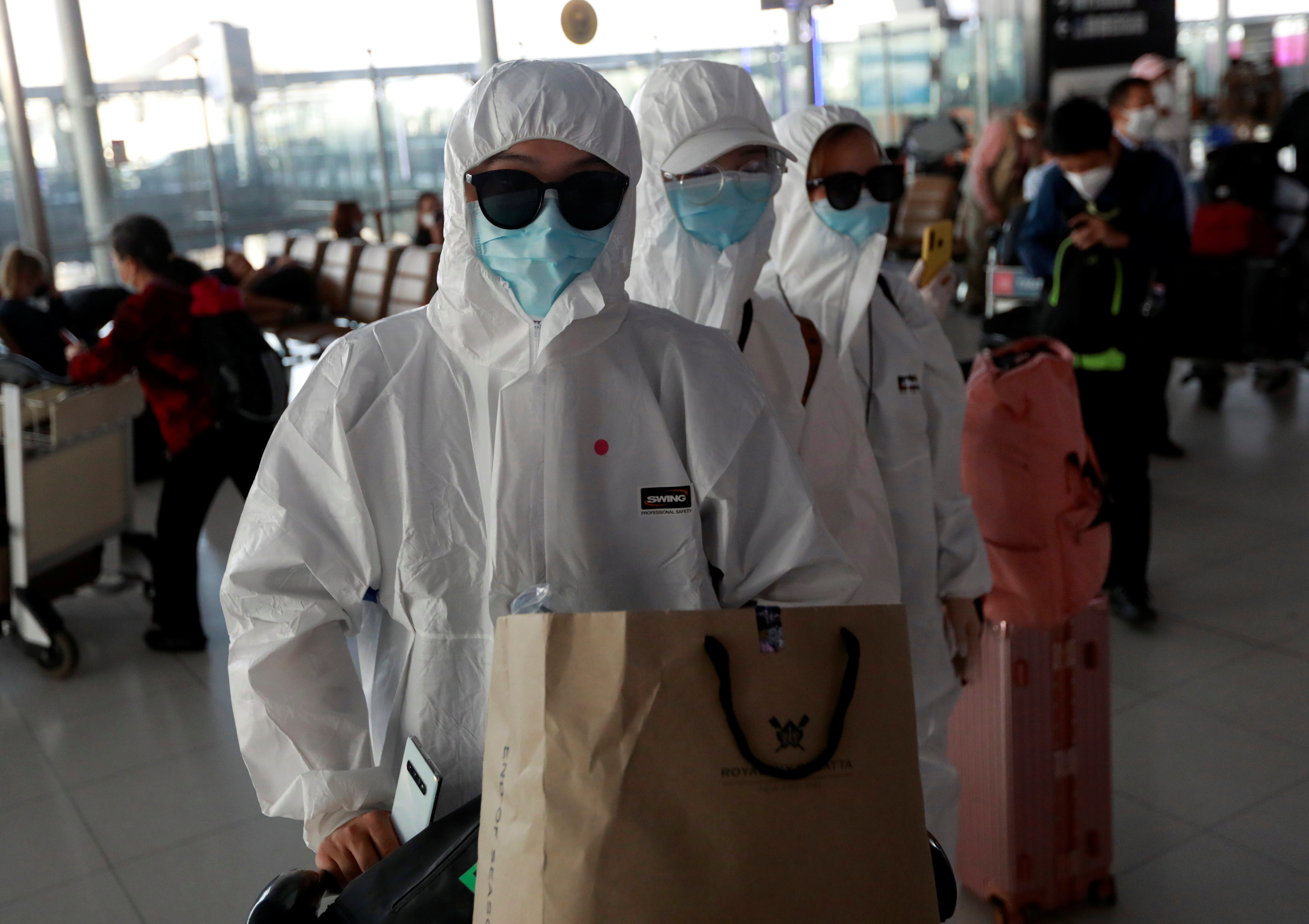Passengers in protective suits are seen before they check in at Suvarnabhumi Airport in Bangkok on March 24, 2020. Photo: Reuters 