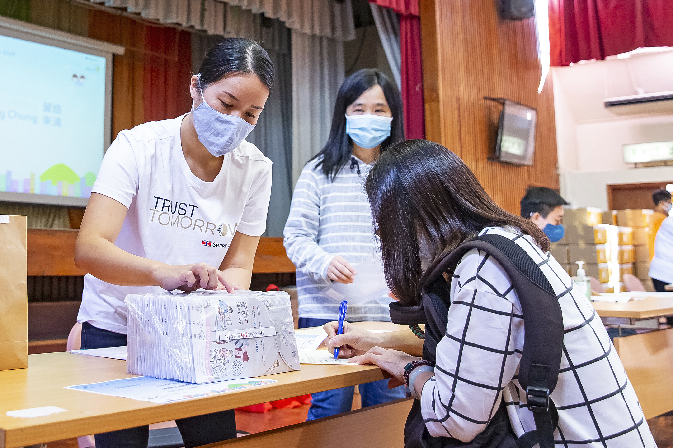 A TrustTomorrow volunteer (left) distributes care packs at a community event.