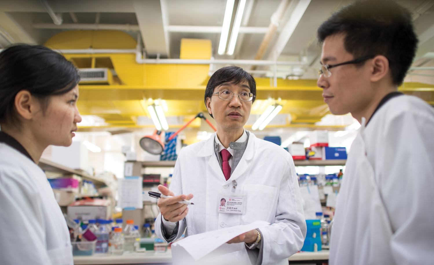 Professor YUEN Kwok-yung discusses with students in a laboratory.
