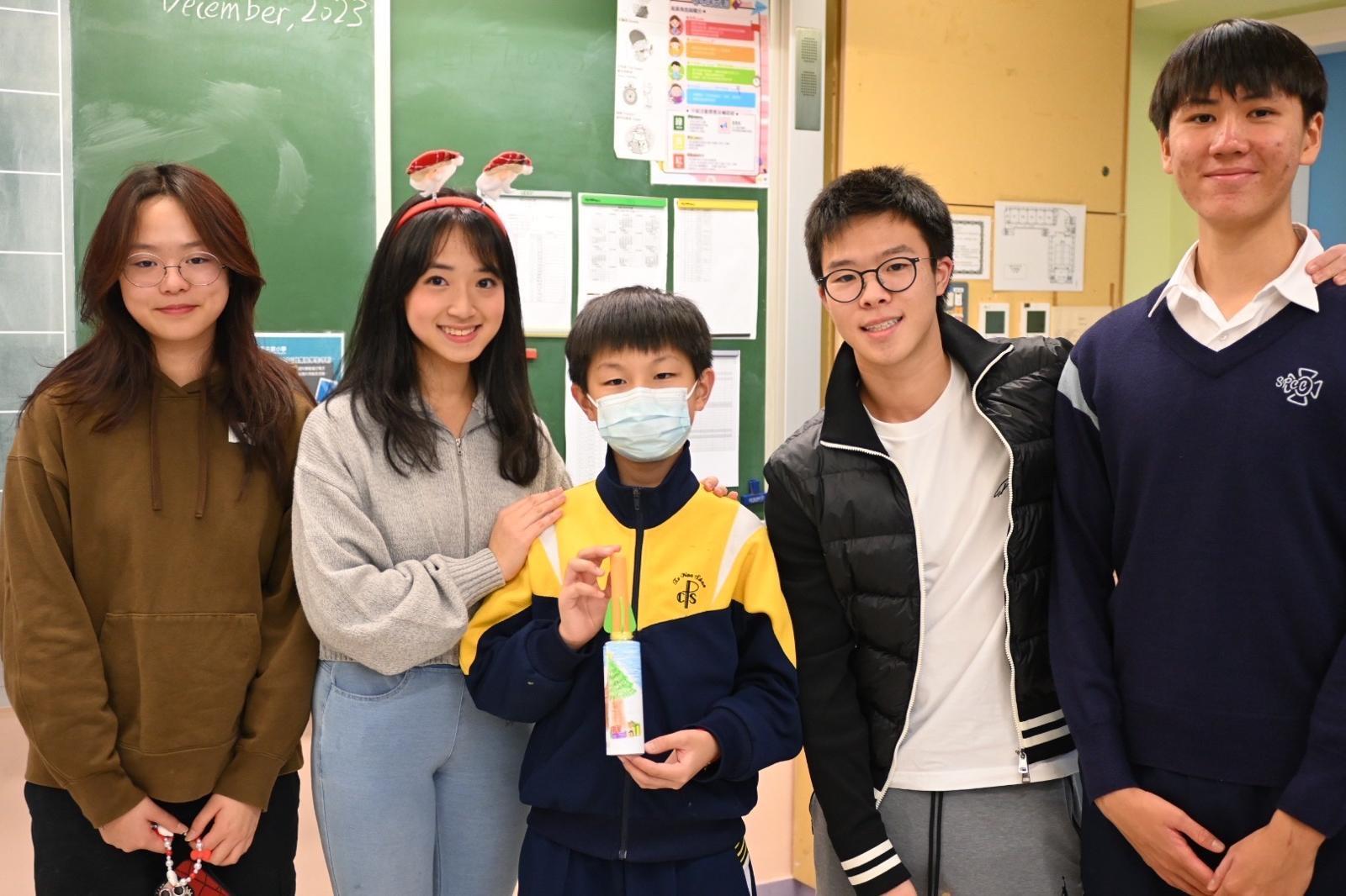 Programme’s founders and designers Ethan Chong (second from right), Isabelle Chan (second from left), and Nathan So (first from right) pose with the winner of the paper rocket design competition.